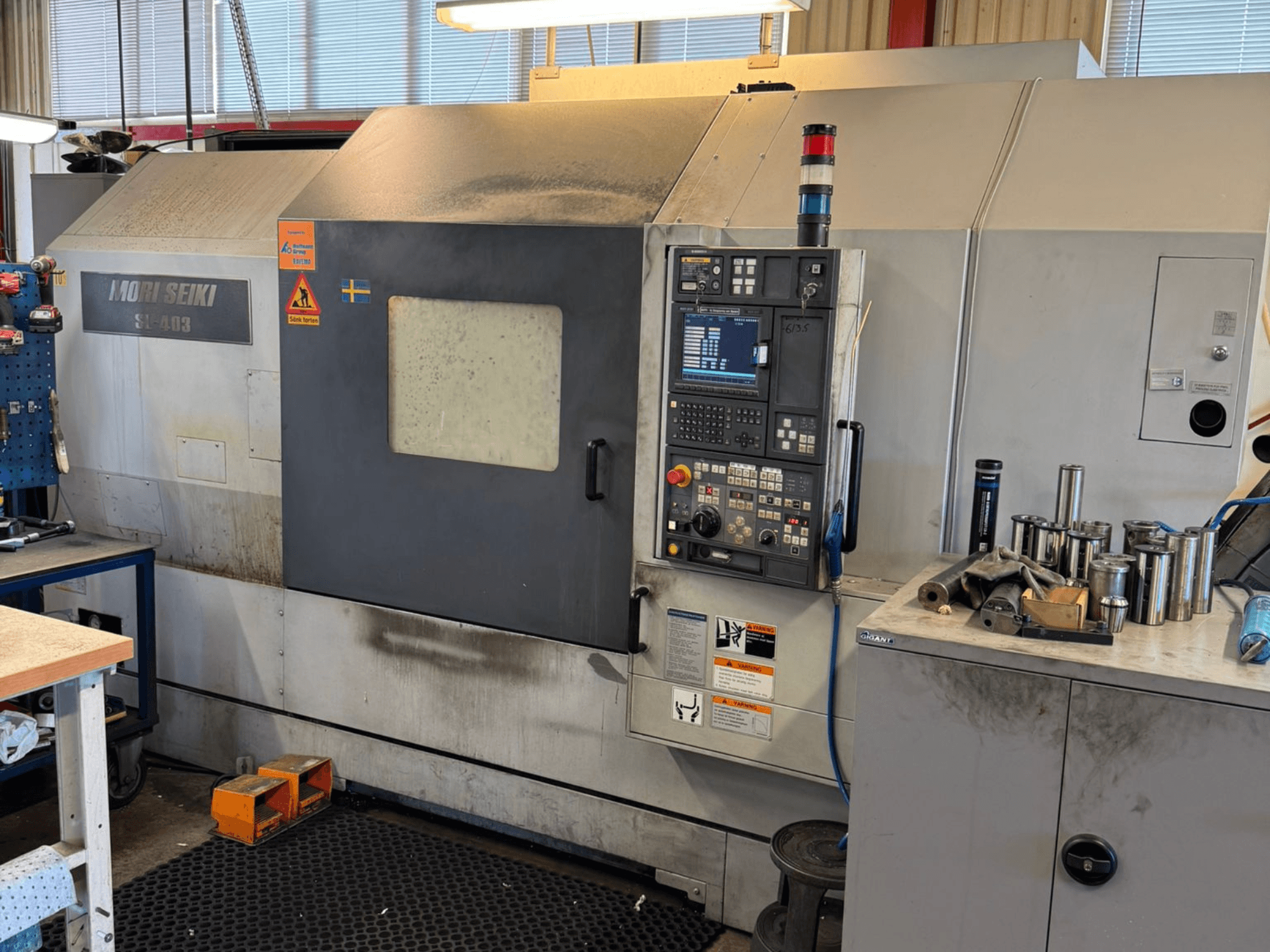 Tokarka pozioma MORI SEIKI SL-403BMC/800 w warsztacie, pokazująca panel sterowania i pobliskie narzędzia, widok z boku.