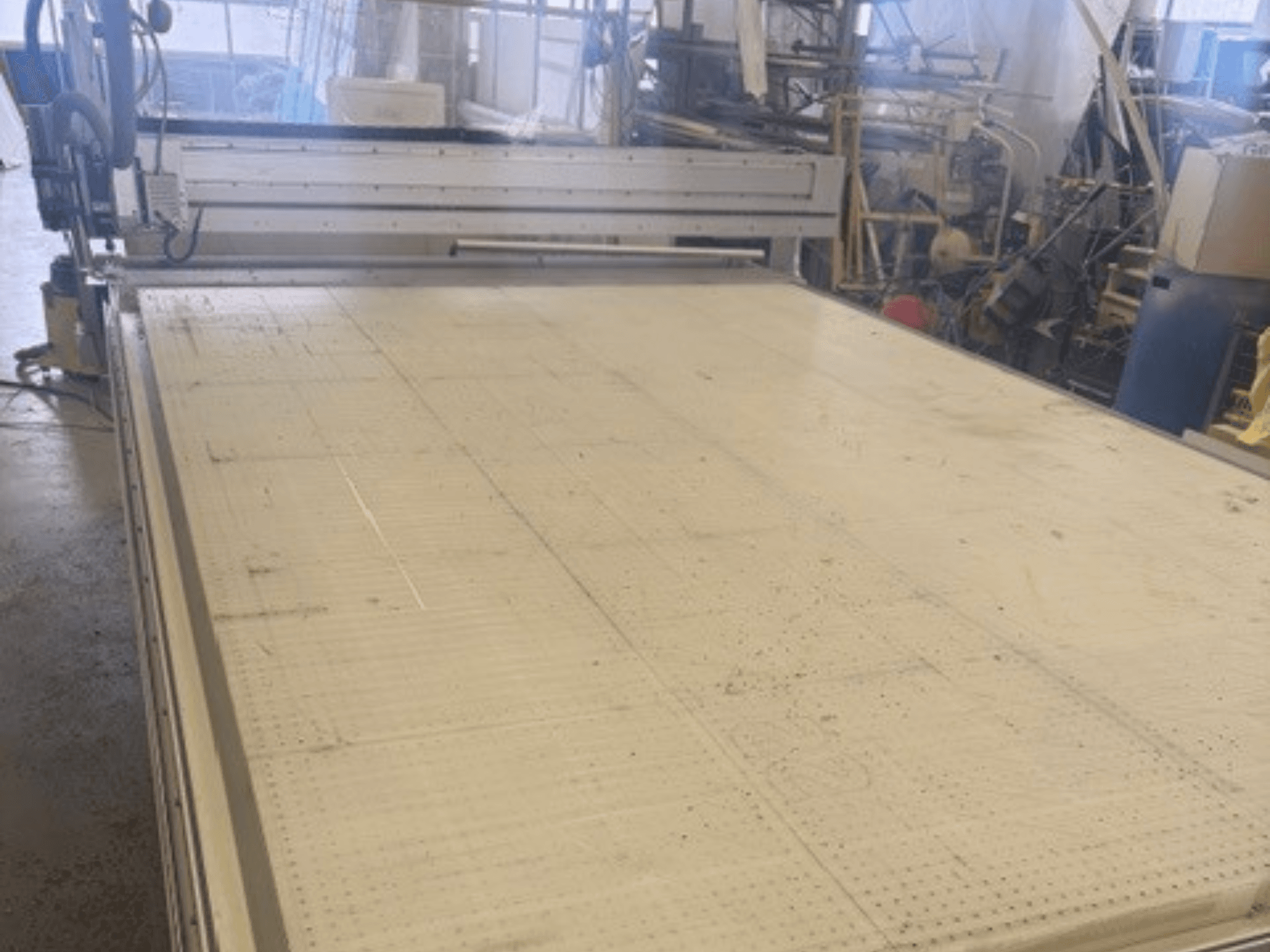 Duża maszyna do cięcia z płaską powierzchnią, pokazująca ramę i szynę prowadzącą; widziana pod kątem w warunkach warsztatowych.