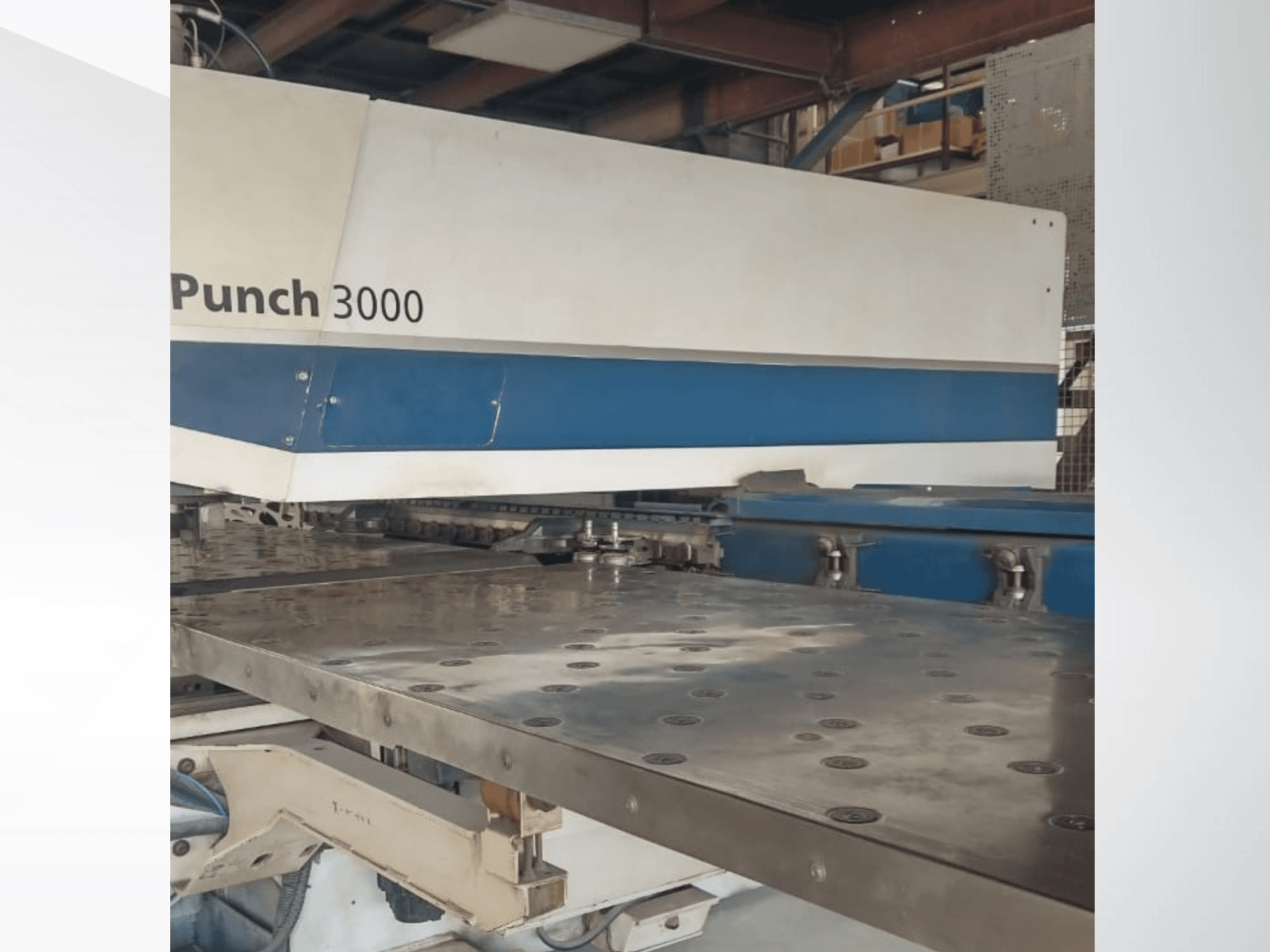 Maszyna Punch 3000 w warsztacie, widok z przodu, prezentująca dużą, płaską metalową powierzchnię z wieloma otworami.