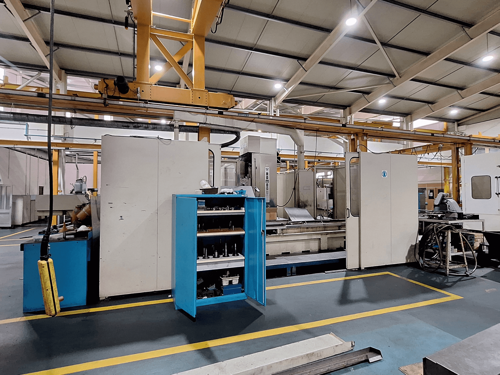 Frezarka bramowa Rambaudi RX 1250, widok z przodu z magazynem narzędzi, w przestronnej przemysłowej przestrzeni roboczej.