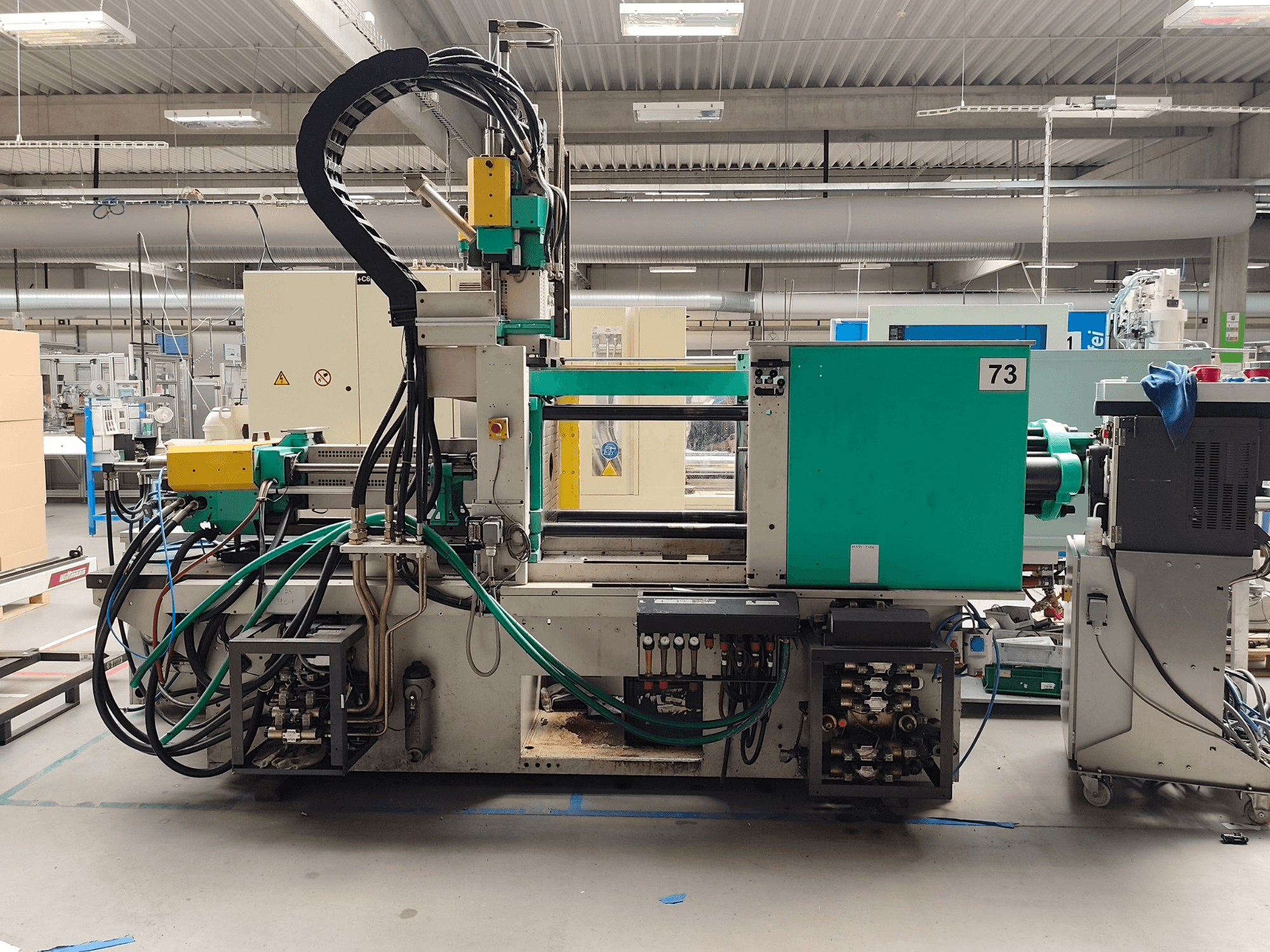 Hydrauliczna wtryskarka Arburg 420 C 1000-150/60, widok z boku, z widocznymi przyłączami hydraulicznymi i elementami sterującymi.
