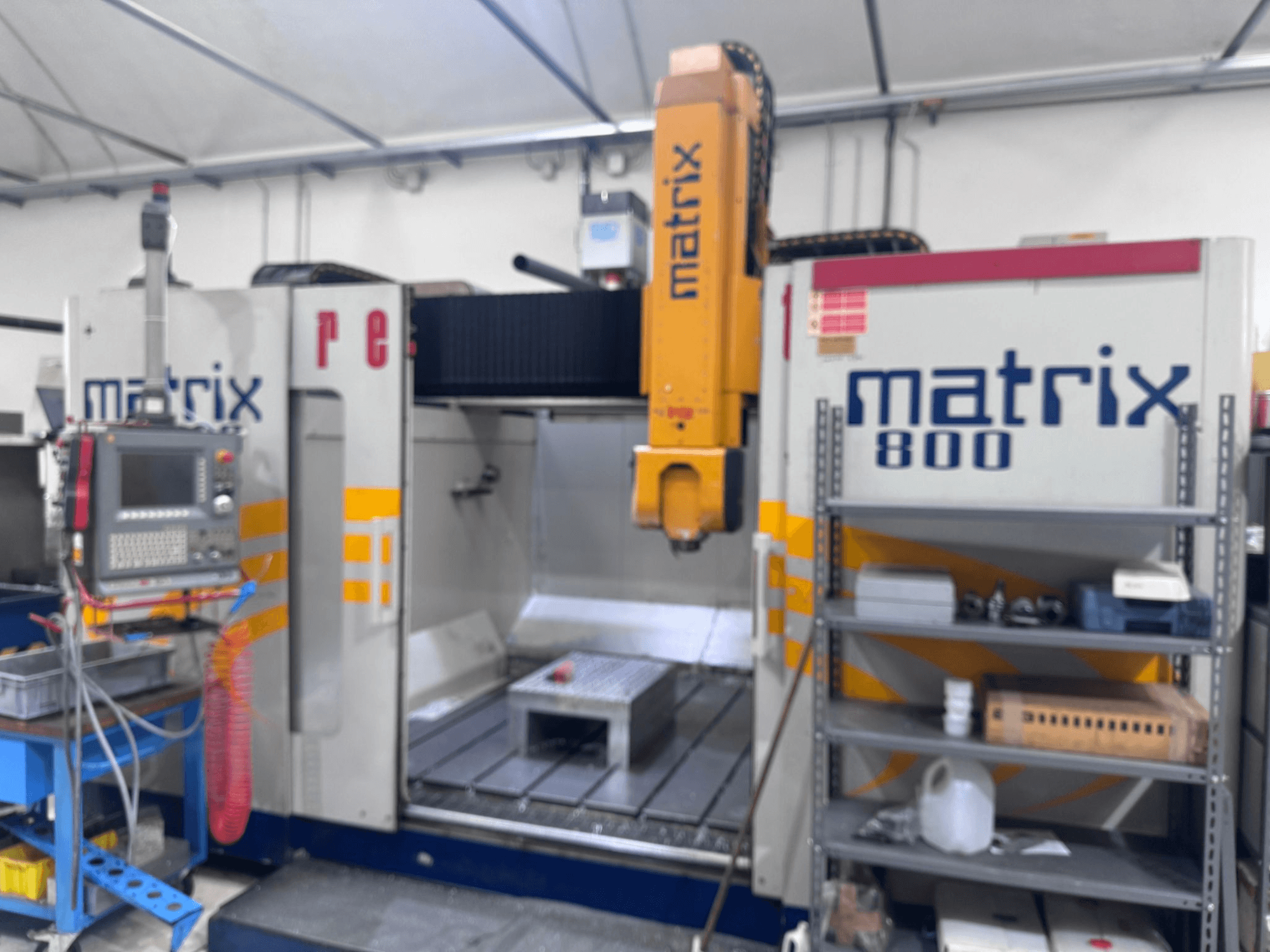 Maszyna CNC Matrix 800 w widoku warsztatowym, z panelem sterowania, narzędziami i stołem roboczym z różnymi obiektami.