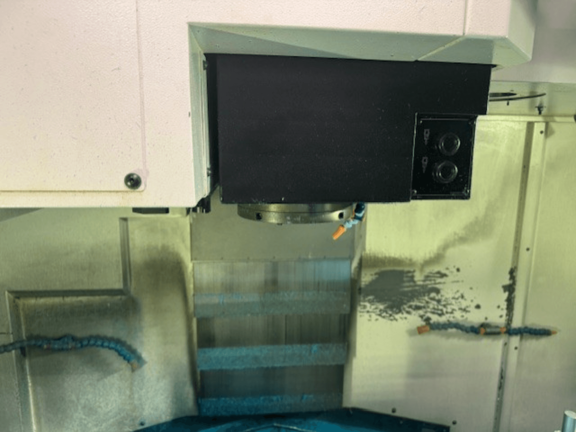 Zbliżenie panelu sterowania frezarki CNC i uchwytu narzędziowego, prezentujące szczegóły marki, przyciski i powierzchnię roboczą.