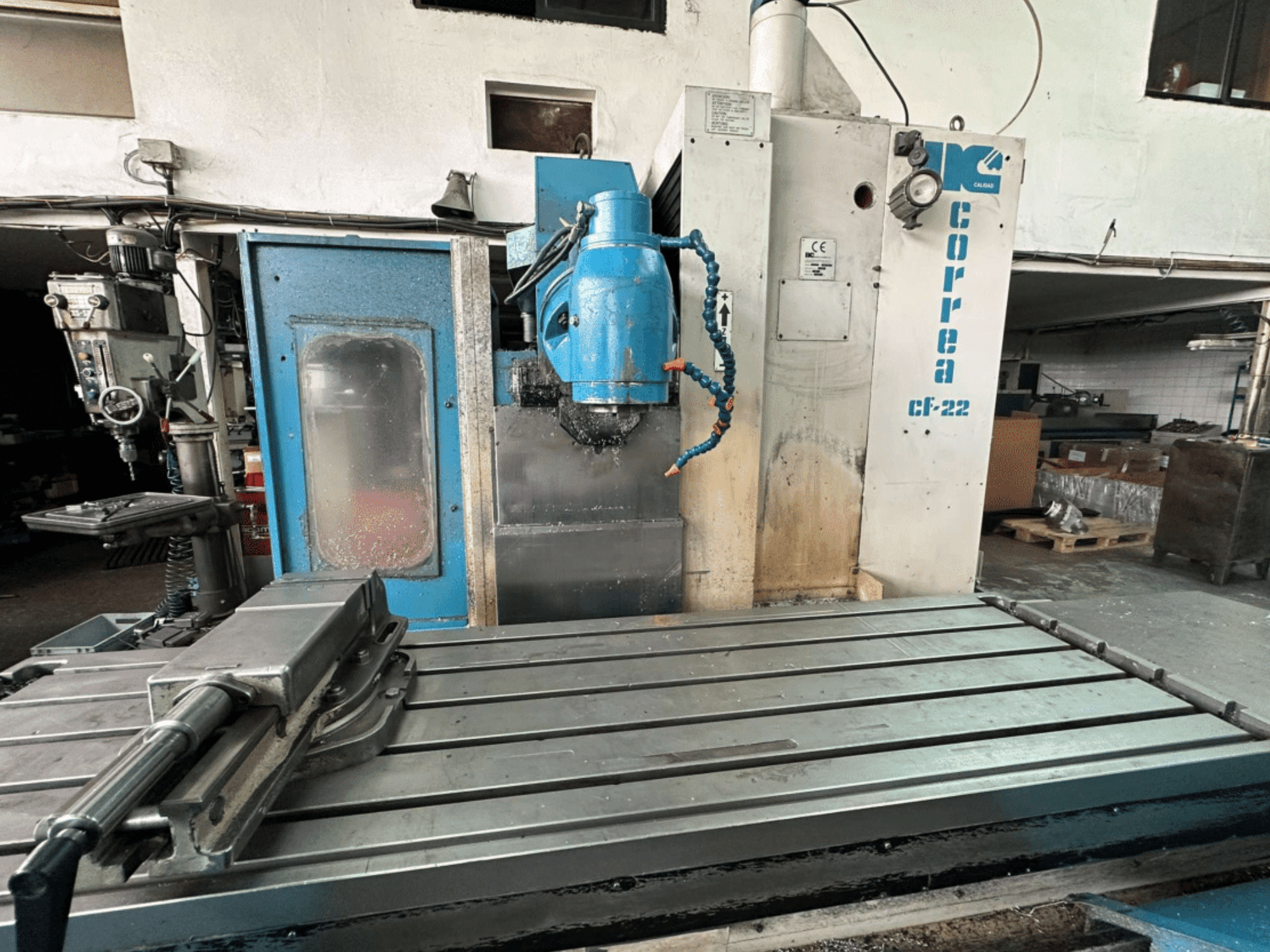 Frezarka Correa CF-22 w widoku z przodu, w niebiesko-srebrnej obudowie, z przesuwanym stołem i głowicą tnącą.