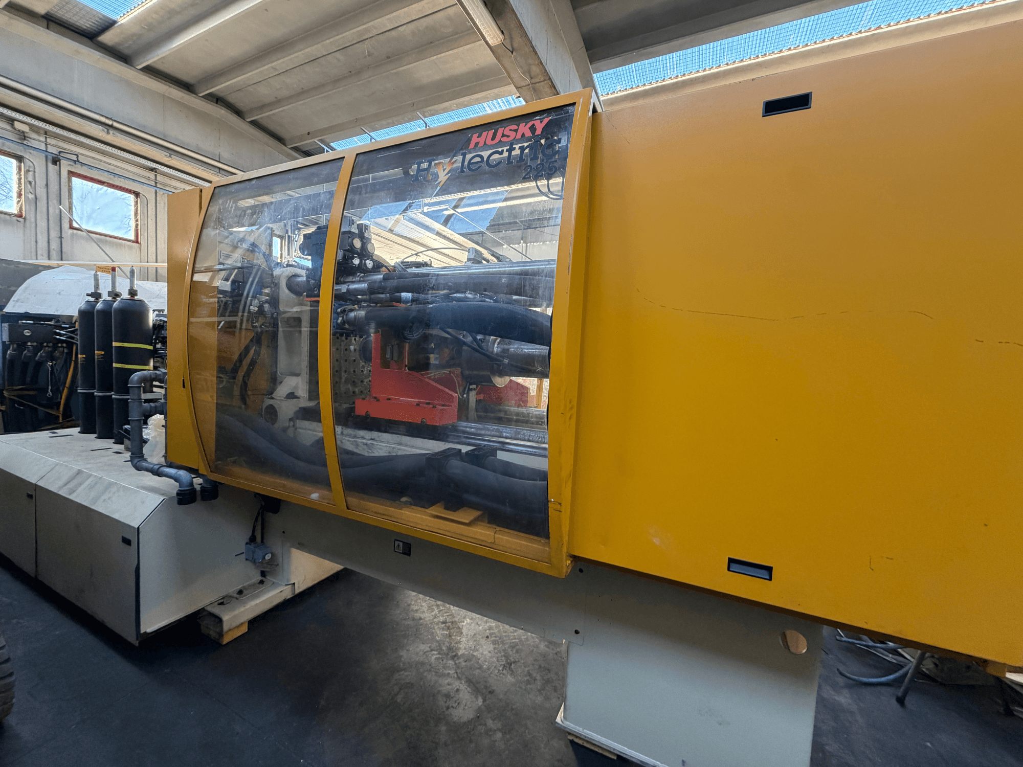 Elektryczna wtryskarka Husky HL225 RS65, widok z przodu z żółtą obudową, widocznym panelem sterowania i elementami hydraulicznymi.