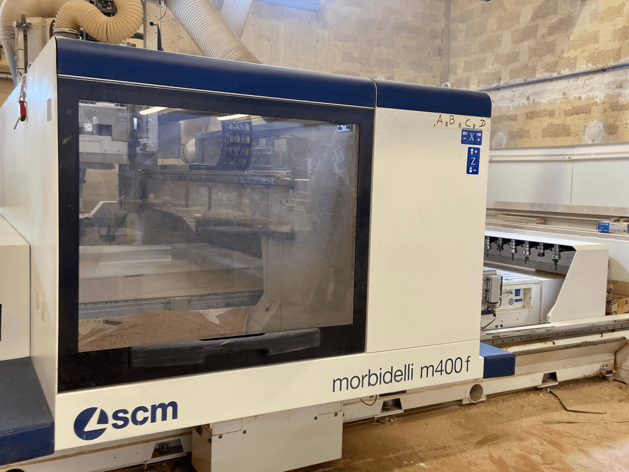 Maszyna CNC SCM Morbidelli M400F, widok z przodu, z panelem sterowania i widocznymi trocinami na podłodze.