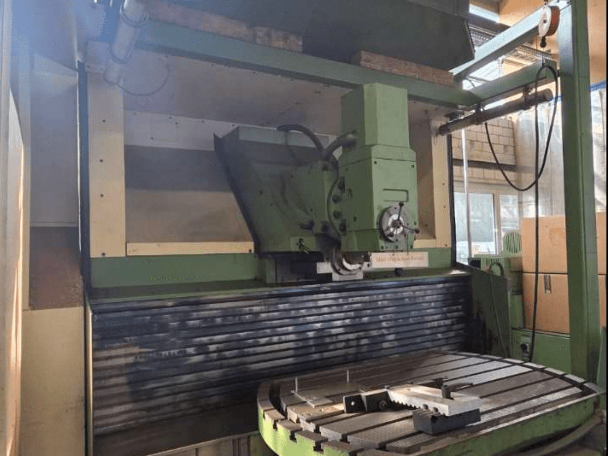 Uniwersalne centrum obróbcze MAHO MH1000 C w widoku z przodu, prezentujące zieloną strukturę, wrzeciono i stół obrotowy z obrabianym przedmiotem.