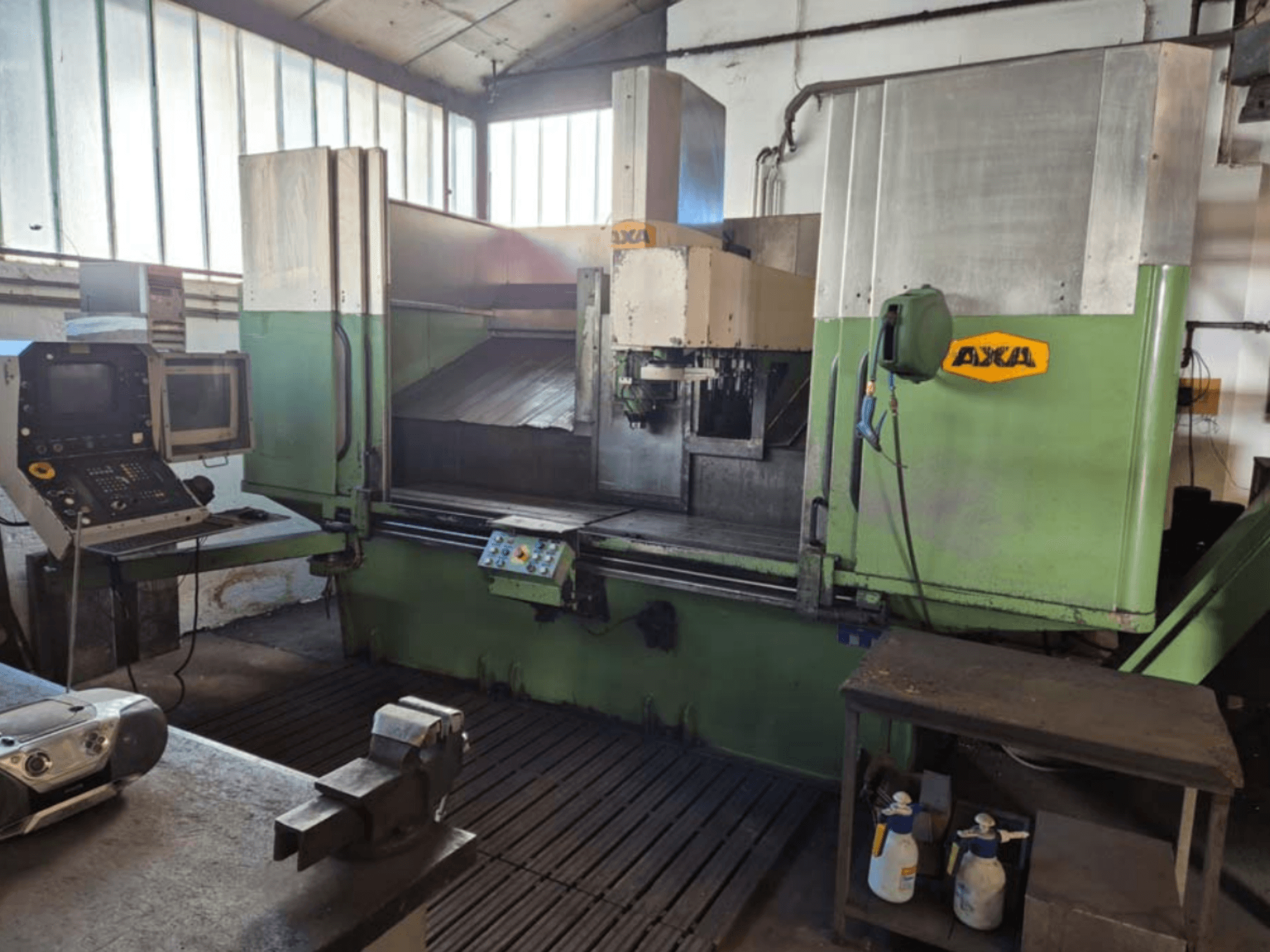 Pionowe centrum obróbcze AXA VSC-2M, widok z przodu, z panelem sterowania i obszarem roboczym z narzędziami tnącymi i środkami czyszczącymi.