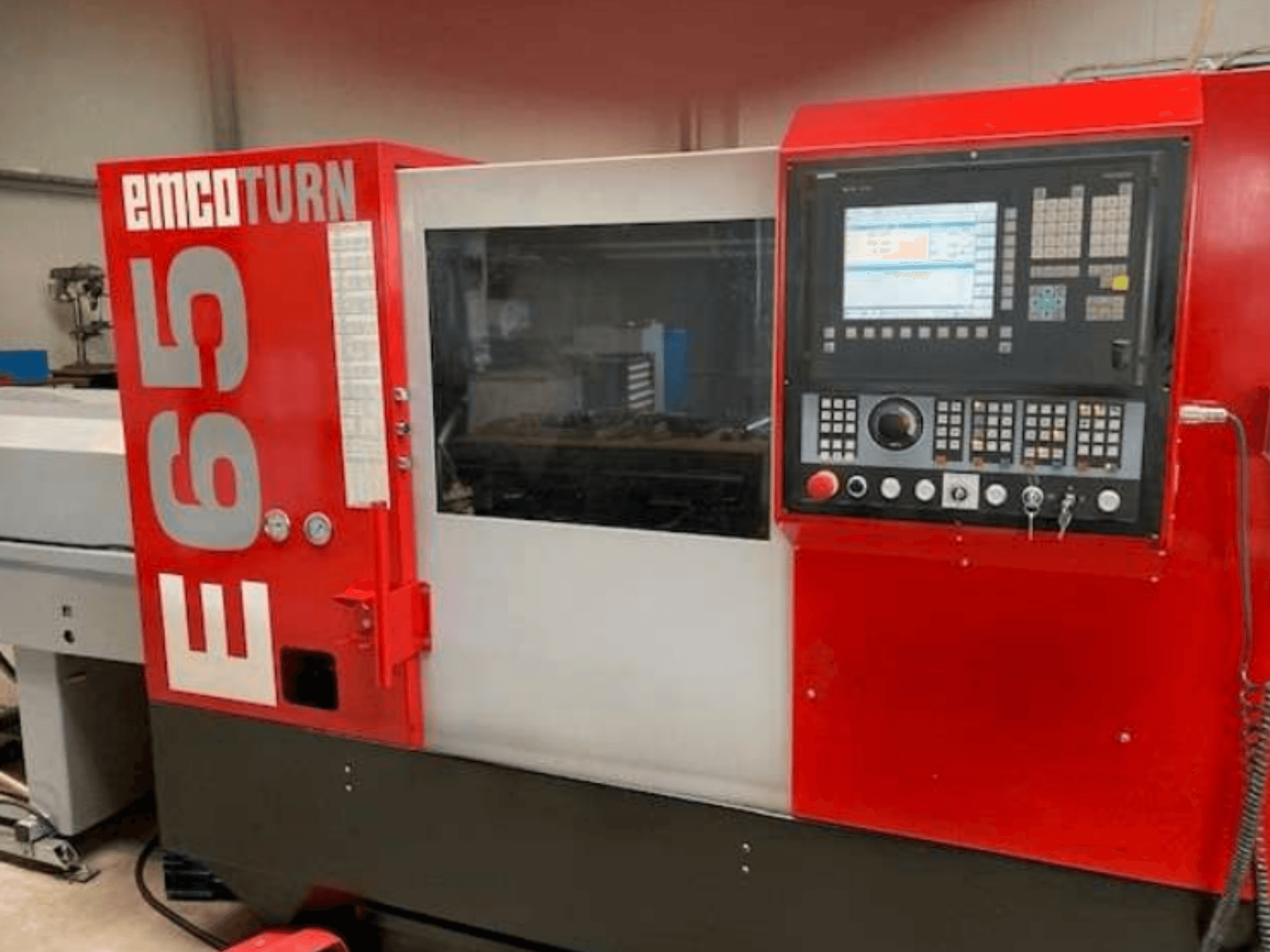 Tokarka CNC EMCO Turn E65, widok z przodu przedstawiający panel sterowania, duży wyświetlacz i obszar roboczy za szybą.