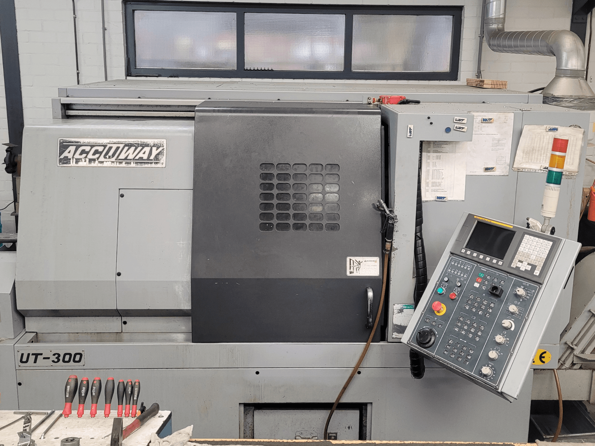 Maszyna CNC Accuway UT-300 w widoku z przodu, z panelem sterowania i różnymi przyciskami operacyjnymi, w warunkach warsztatowych.