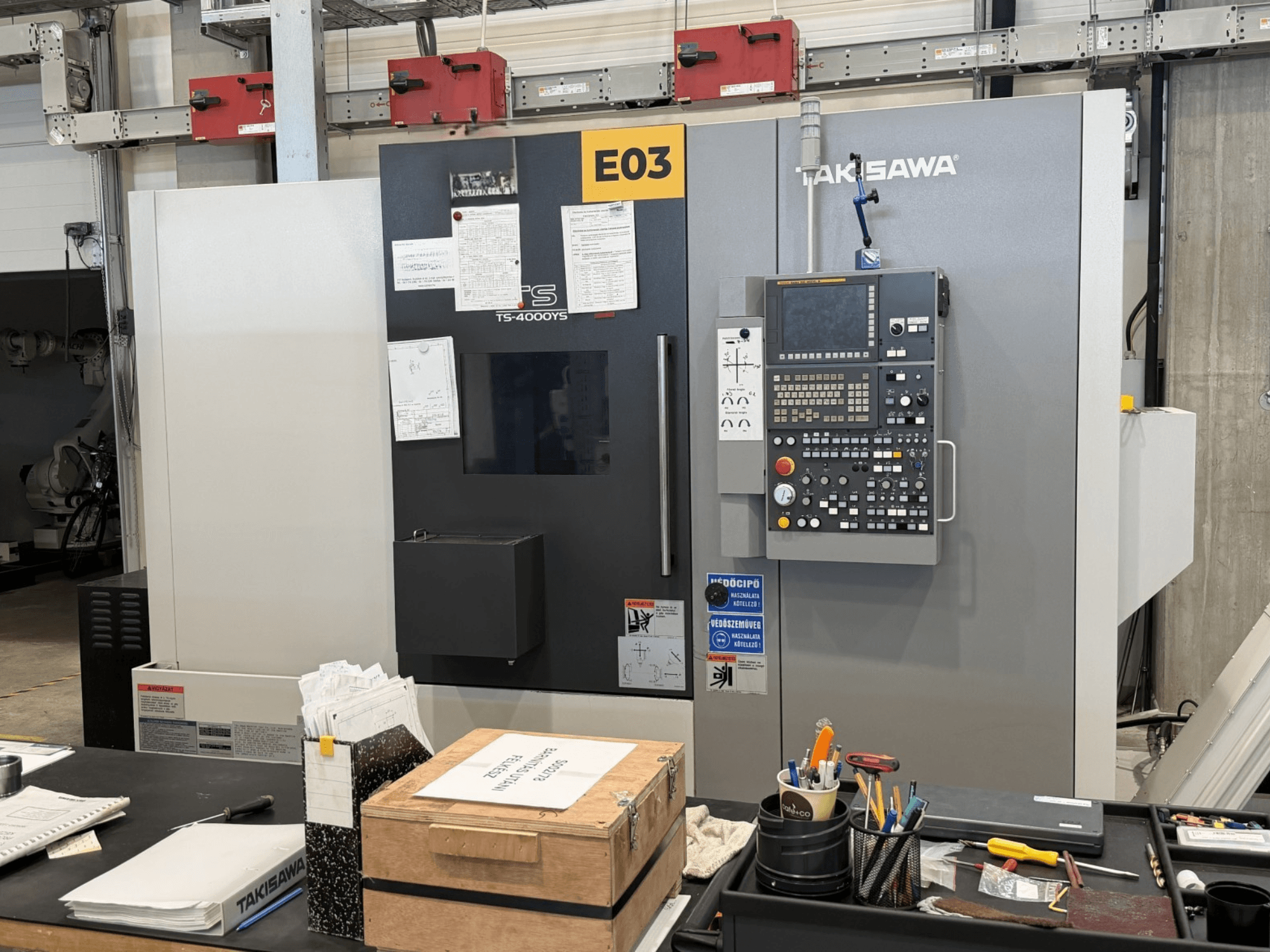 Centrum tokarsko-frezarskie Takisawa TS-4000YS widziane z przodu, z widocznym panelem sterowania i dokumentami z boku.