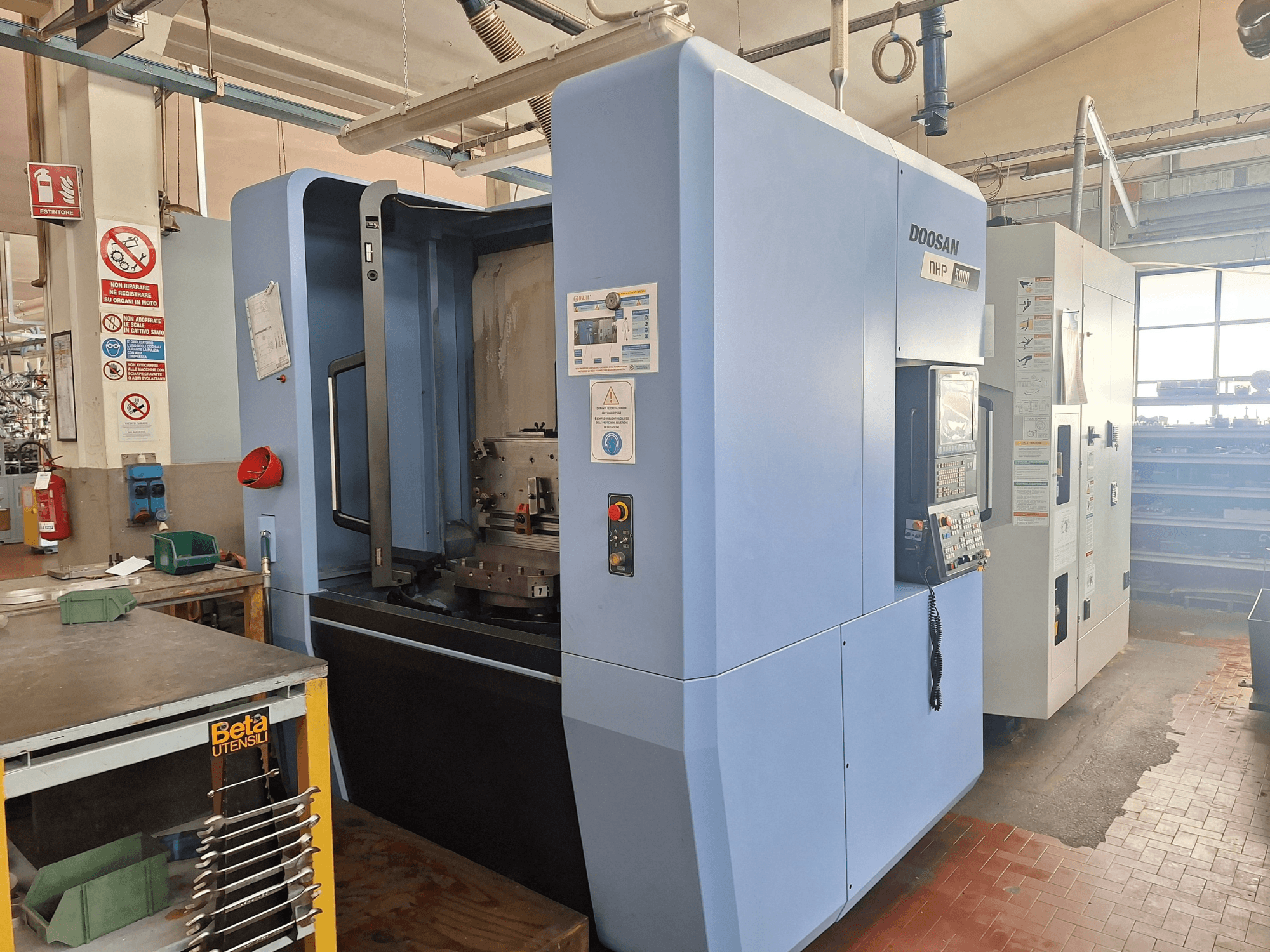 Poziome centrum obróbcze DOOSAN NHP 5000 w warsztacie, widok z boku przedstawiający panel sterowania i obszar obróbki.