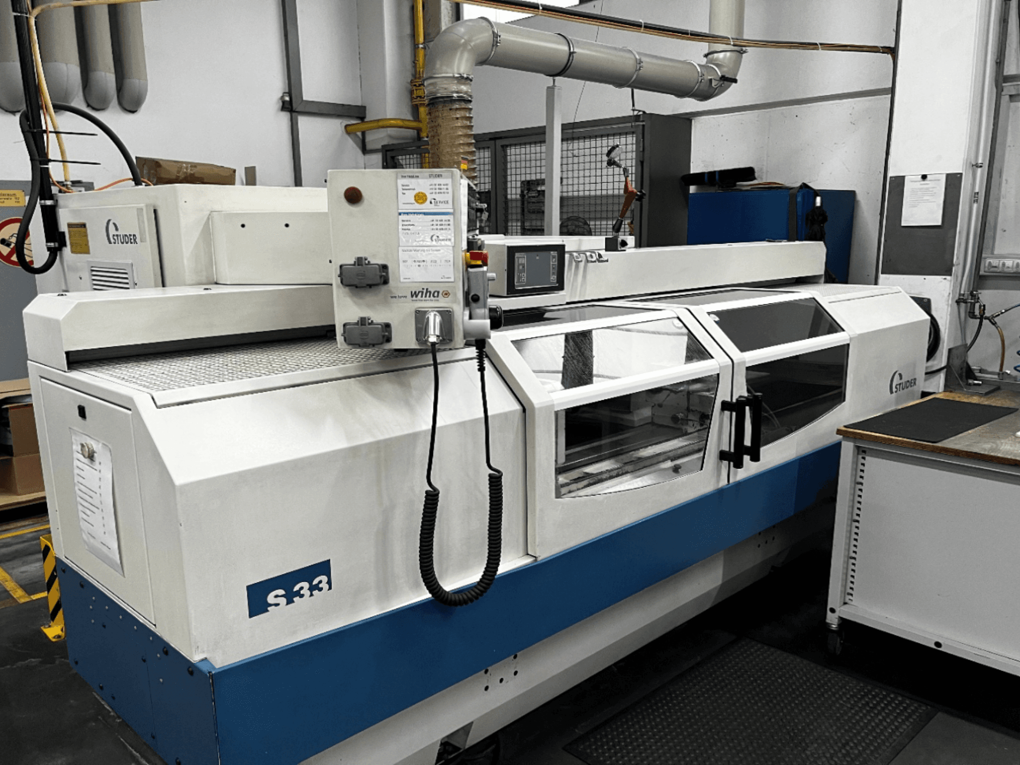 Szlifierka cylindryczna CNC STUDER S33, widok z przodu; posiada panel sterowania i szklane drzwi bezpieczeństwa. Ustawienie przemysłowe.