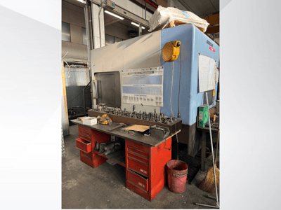 Centrum obróbcze Doosan z czerwonym stołem roboczym i schowkiem na narzędzia i sprzęt, widziane od przodu.