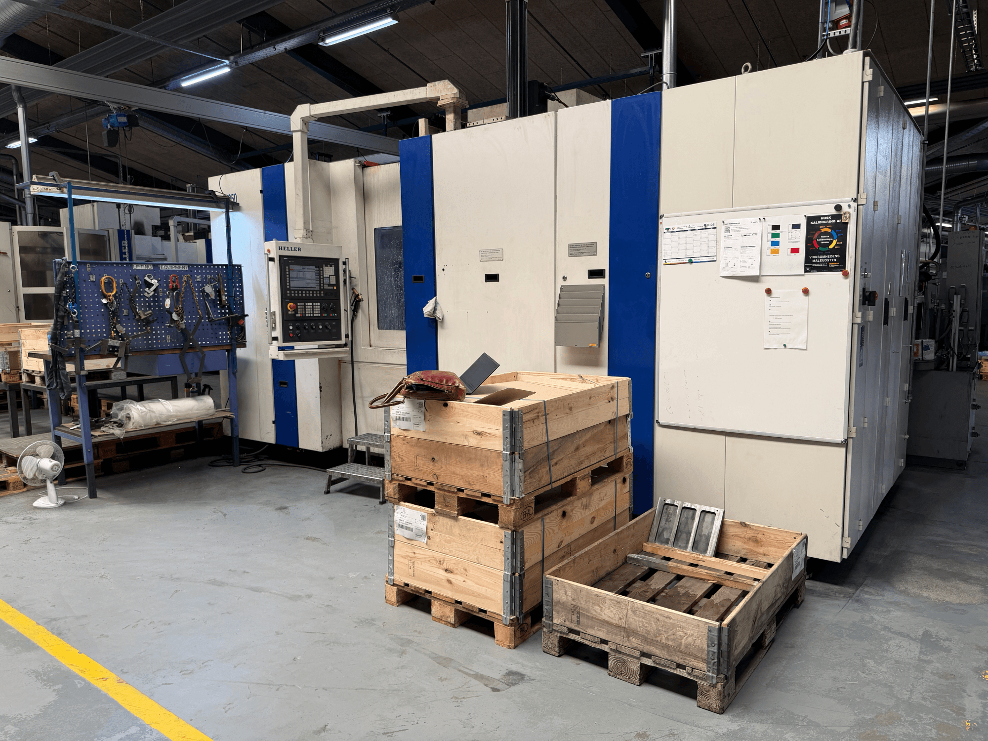 POZIOME CENTRUM OBRÓBCZE HELLER MCH 250 w warsztacie, widok z boku z widocznymi drewnianymi paletami i stojakiem na narzędzia.