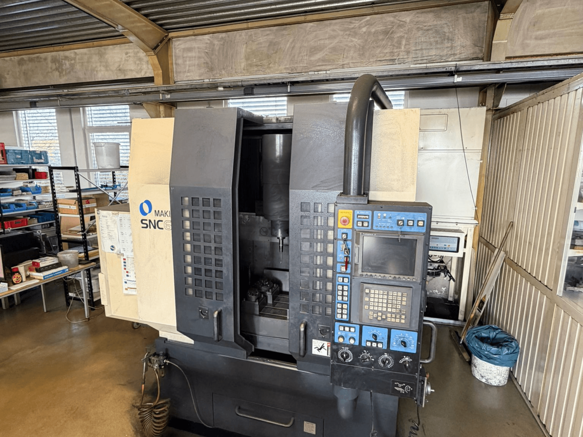 Pionowe centrum obróbcze Makino SNC 64-A15 w widoku z przodu, prezentujące panel sterowania, obszar obróbki i przemysłową przestrzeń roboczą.