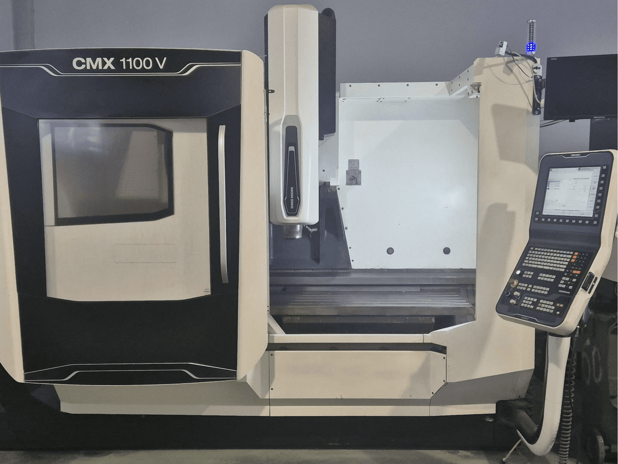 Pionowe centrum obróbcze DMG MORI CMX 1100 V – widok z przodu przedstawiający panel sterowania i łoże maszyny.