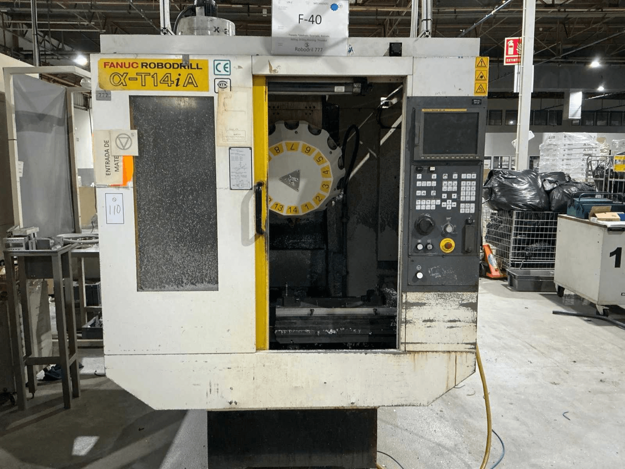 Pionowe centrum obróbcze FANUC ROBODRILL α-T14iB, widok z przodu przedstawiający panel sterowania i karuzelę narzędziową.
