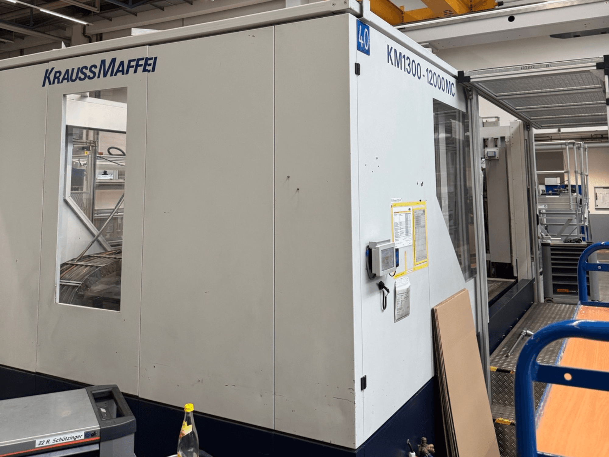 Hydrauliczna wtryskarka Krauss Maffei KM1300-12000 MC, widok z boku, panel sterowania i przestrzeń robocza.