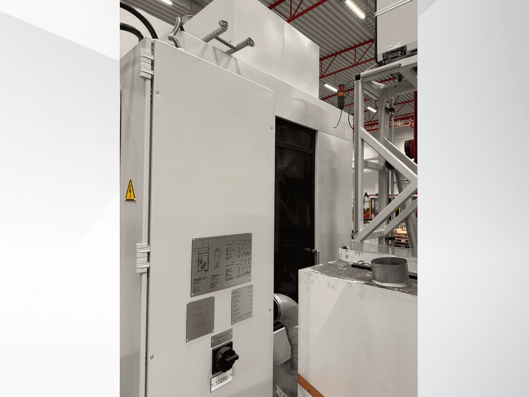 Widok z boku białej maszyny przemysłowej z panelem sterowania i etykietą ostrzegawczą, część zautomatyzowanego systemu.