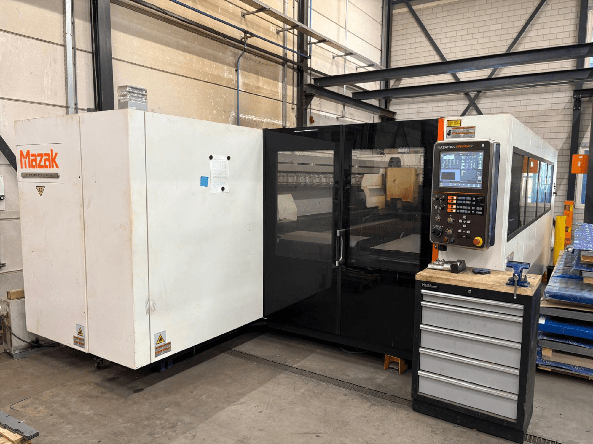 Maszyna do cięcia laserowego CO₂ Mazak Optiplex 3015, widok z przodu, przedstawiający panel sterowania i otoczenie przemysłowe.