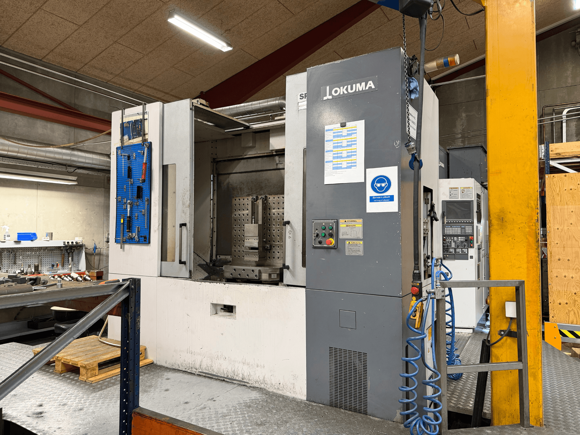 Poziome centrum obróbcze Okuma MA-600HB w warsztacie – widok z przodu przedstawiający panel sterowania i obszar roboczy.