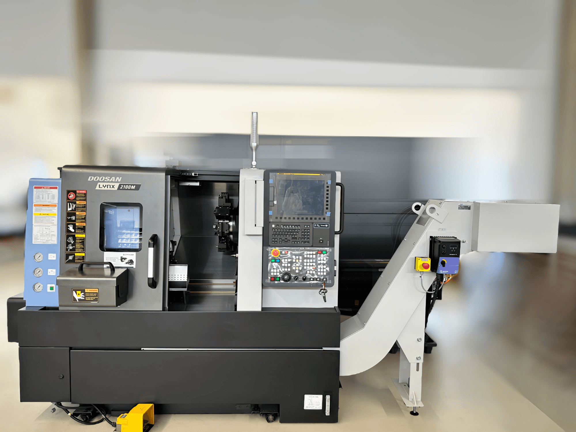 Widok z przodu tokarki poziomej DN SOLUTIONS LYNX 2100MB, pokazujący panel sterowania i szczegóły obszaru roboczego.