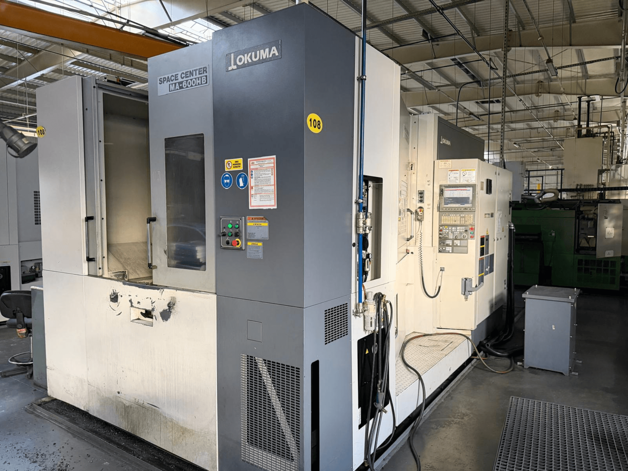 Poziome centrum obróbcze Okuma MA-600 HB, widok z przodu, panel sterowania i obszar cięcia z widocznymi śladami zużycia.