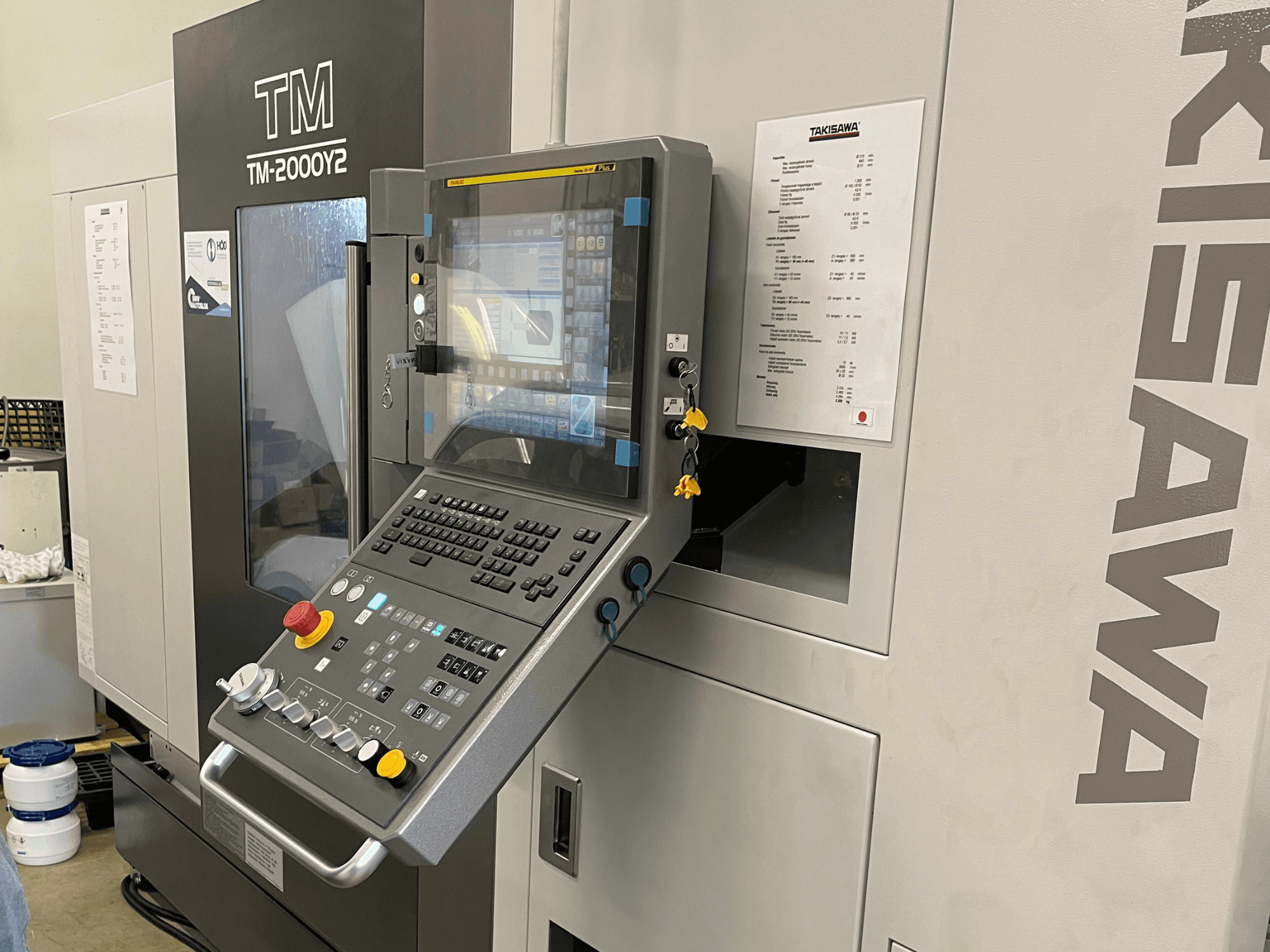 Panel sterowania tokarki poziomej Takisawa TM-2000Y2 w widoku z przodu, z wyświetlaczem cyfrowym i przyciskami operacyjnymi.