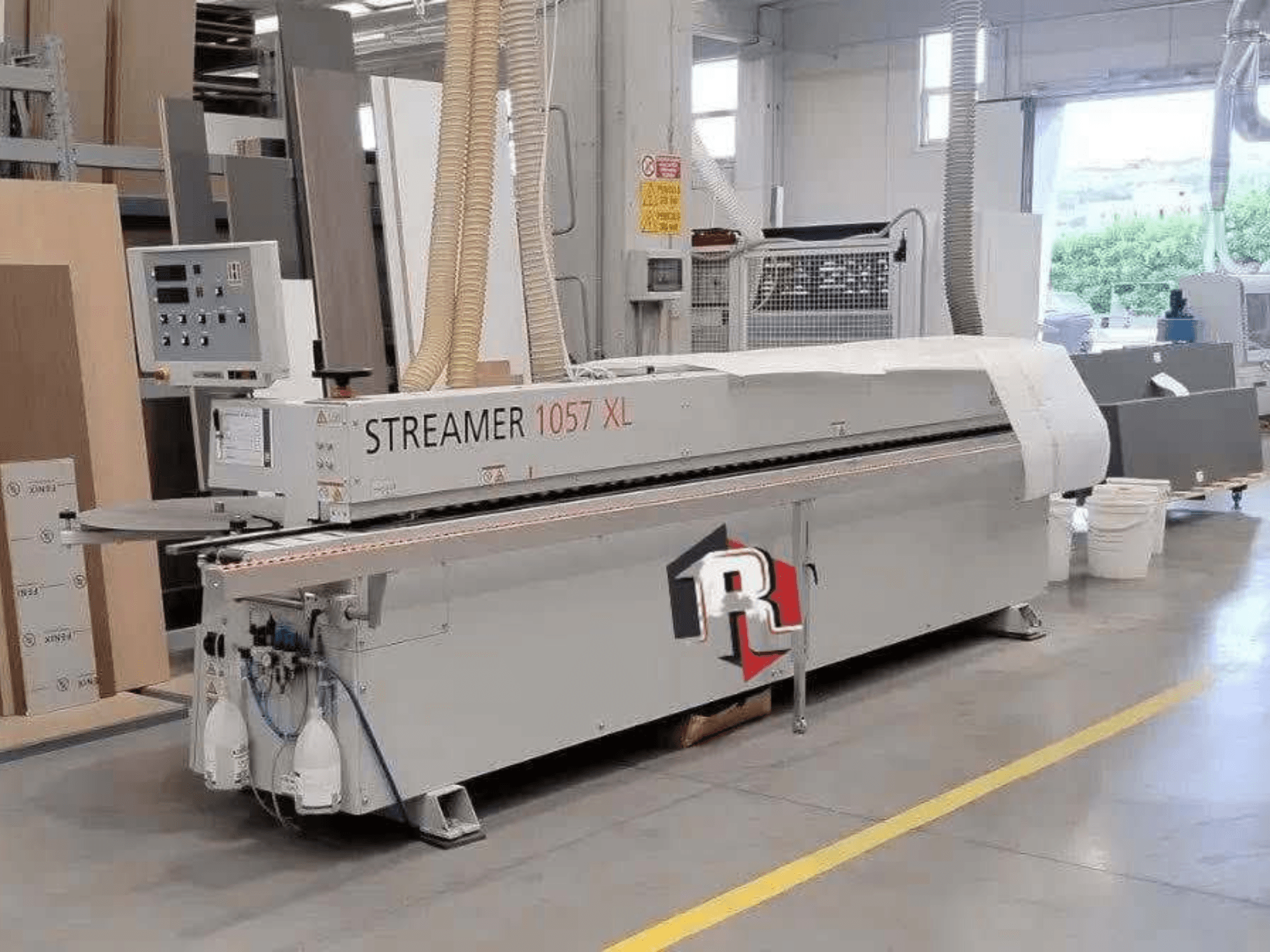 Okleiniarka HOLZHER STREAMER 1057 XL w warsztacie, widok z boku z widocznym panelem sterowania i wężami powietrznymi.