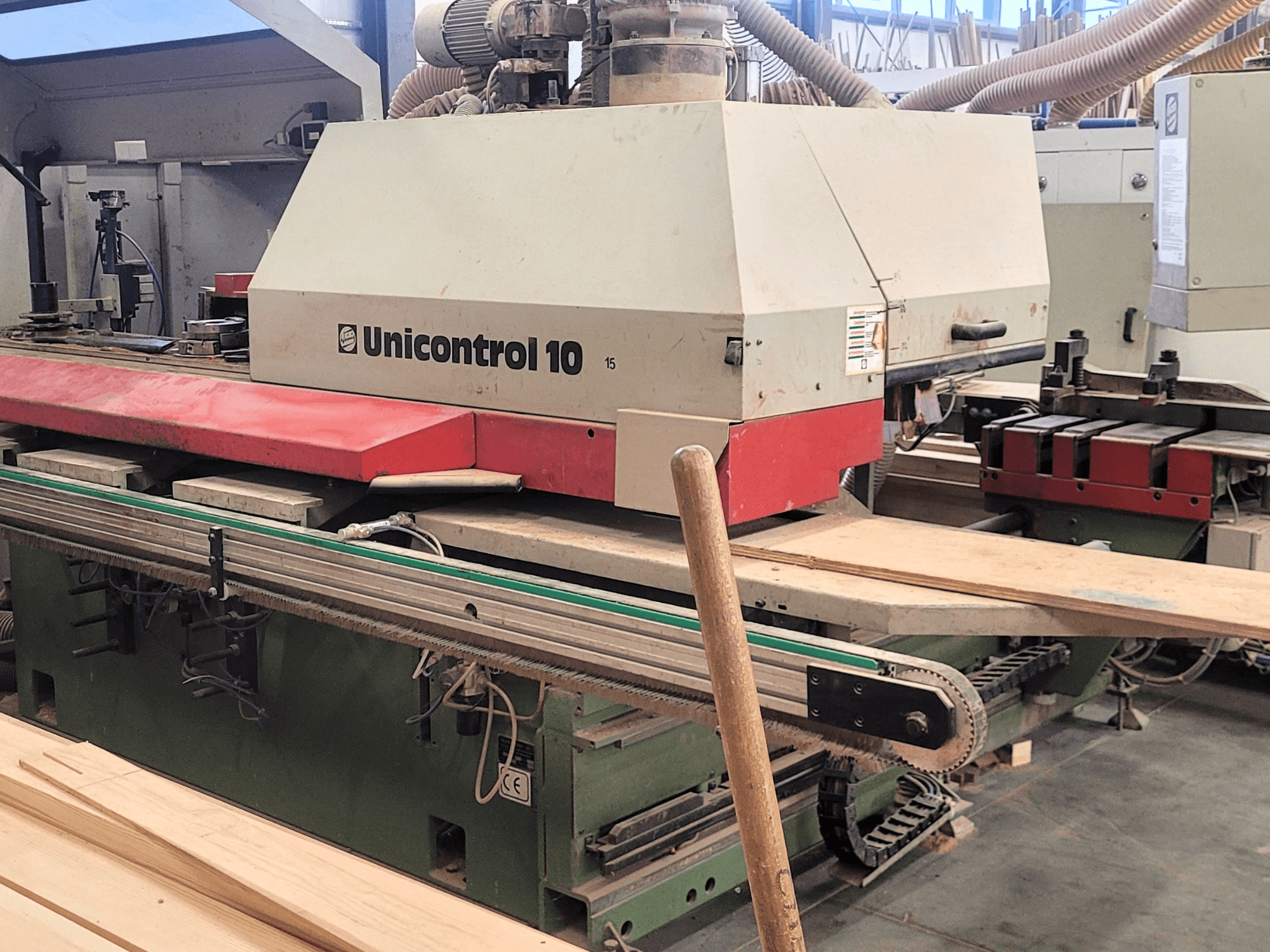 Centrum obróbcze CNC Unicontrol 10 firmy WEINIG/DIMTER, widok z przodu z drewnianymi deskami i wyposażeniem w otoczeniu warsztatu.
