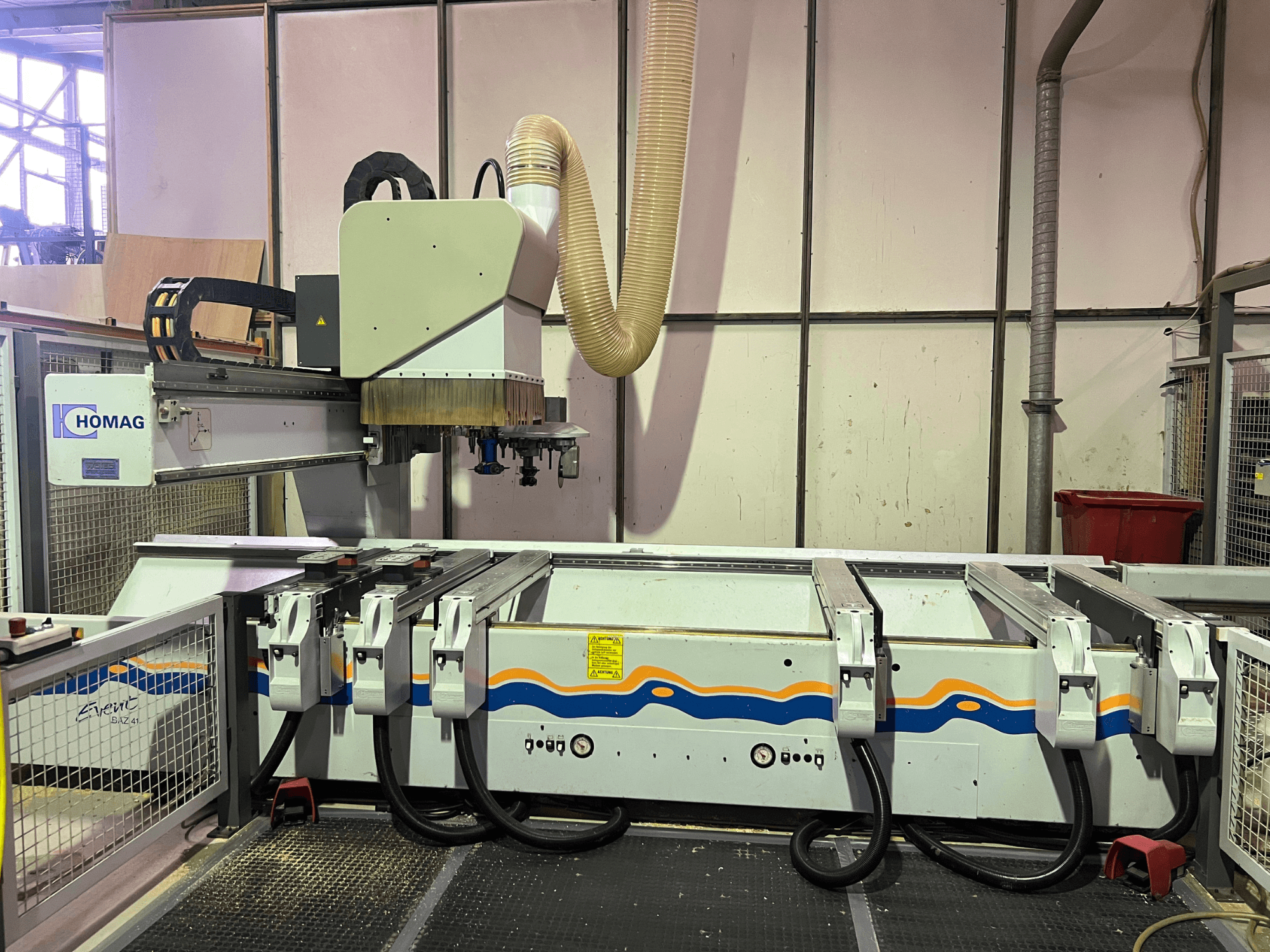 Maszyna CNC HOMAG BIZ 4 w warsztacie; widok z przodu pokazujący system odsysania pyłu i panel sterowania z kablami.