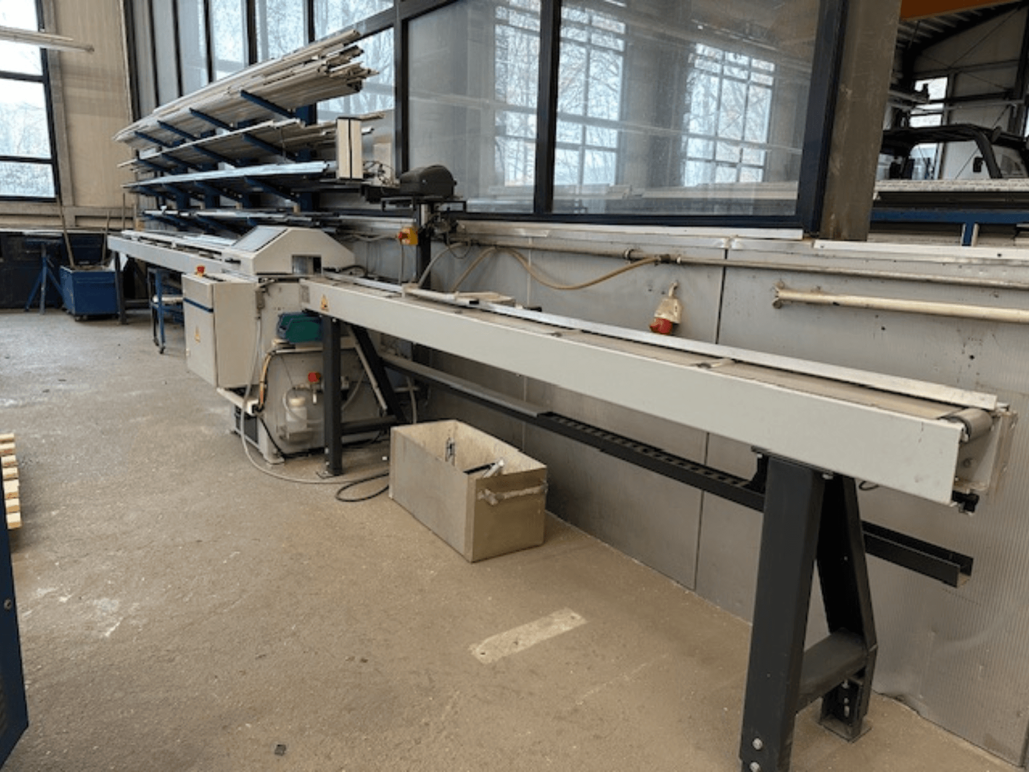 Pilarka tarczowa do metalu SCHÜCO PGS w warsztacie, widok z boku z regulowanym łożem tnącym i półką profili metalowych powyżej.