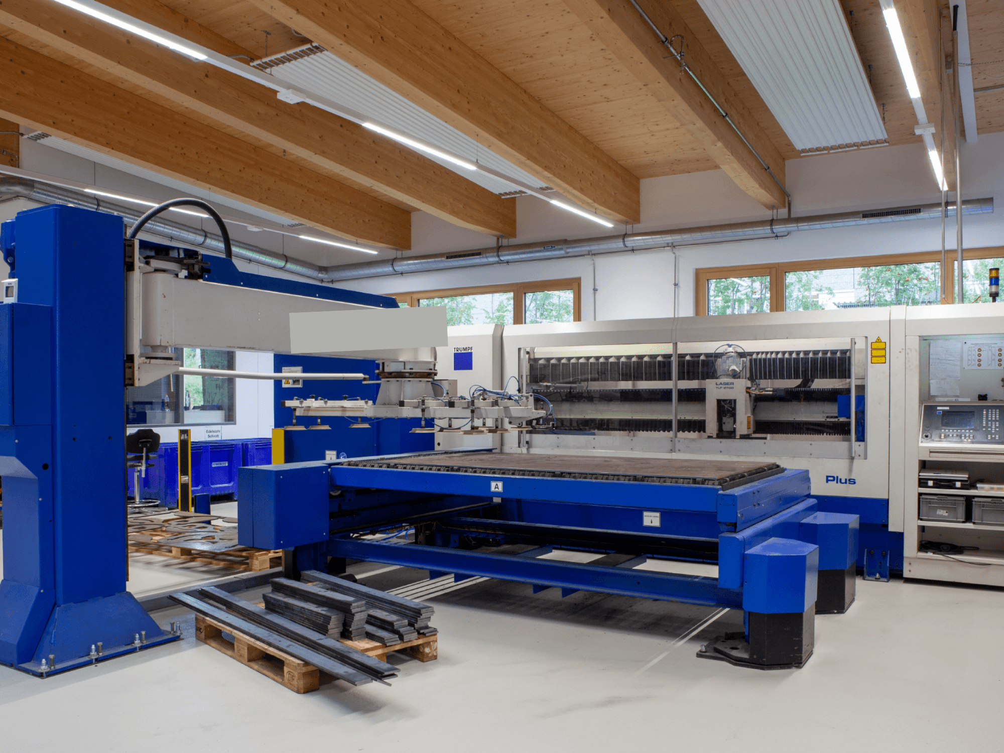 Maszyna do cięcia laserowego CO₂ TRUMPF TRUMATIC L 2530 Plus w warsztacie, charakteryzująca się dużym stołem roboczym i przemysłową konstrukcją.