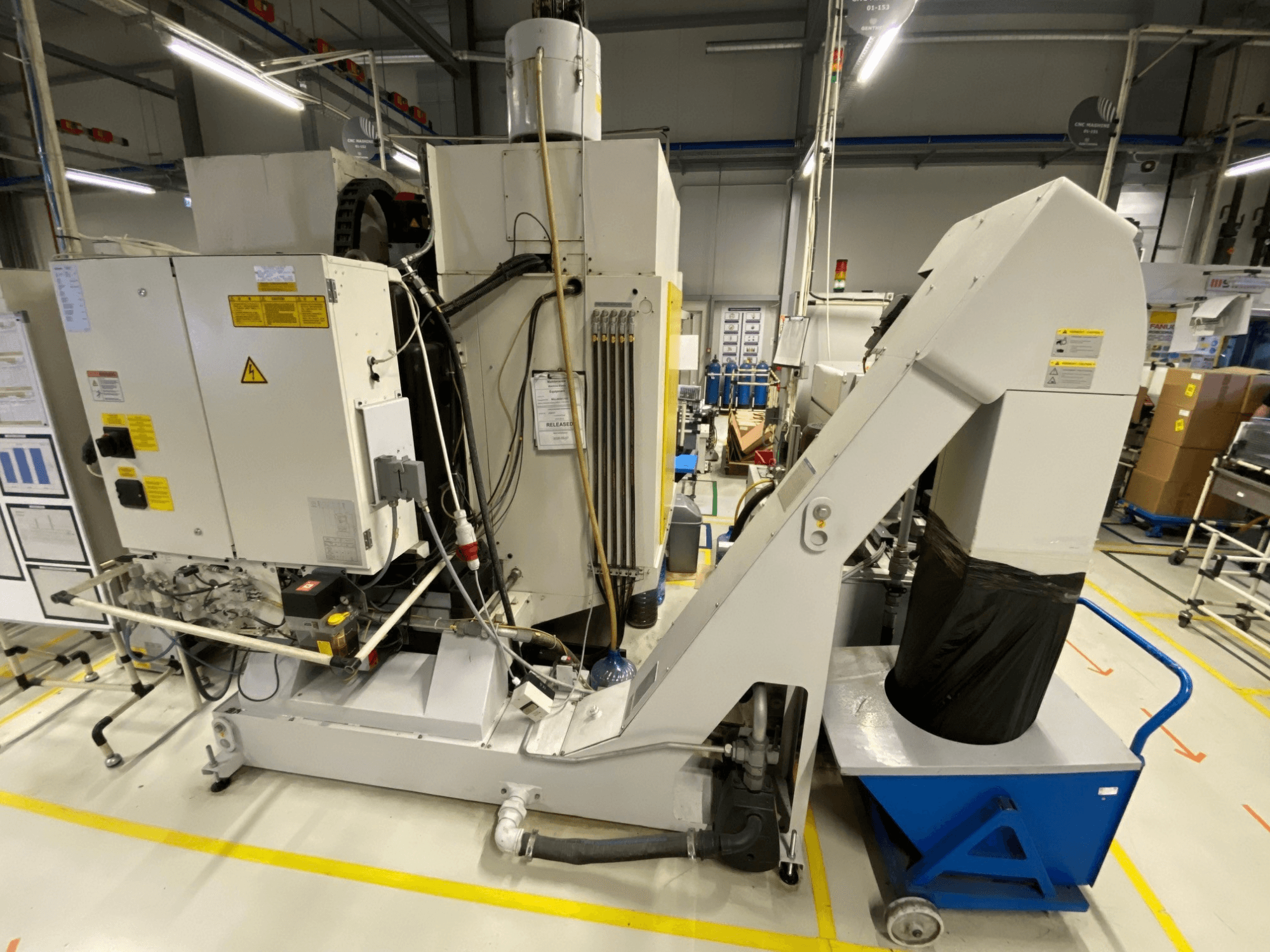 Widok z przodu pionowego centrum obróbczego FANUC ROBODRILL α-D21LiB, przedstawiający elementy elektryczne i rynnę wyładowczą.