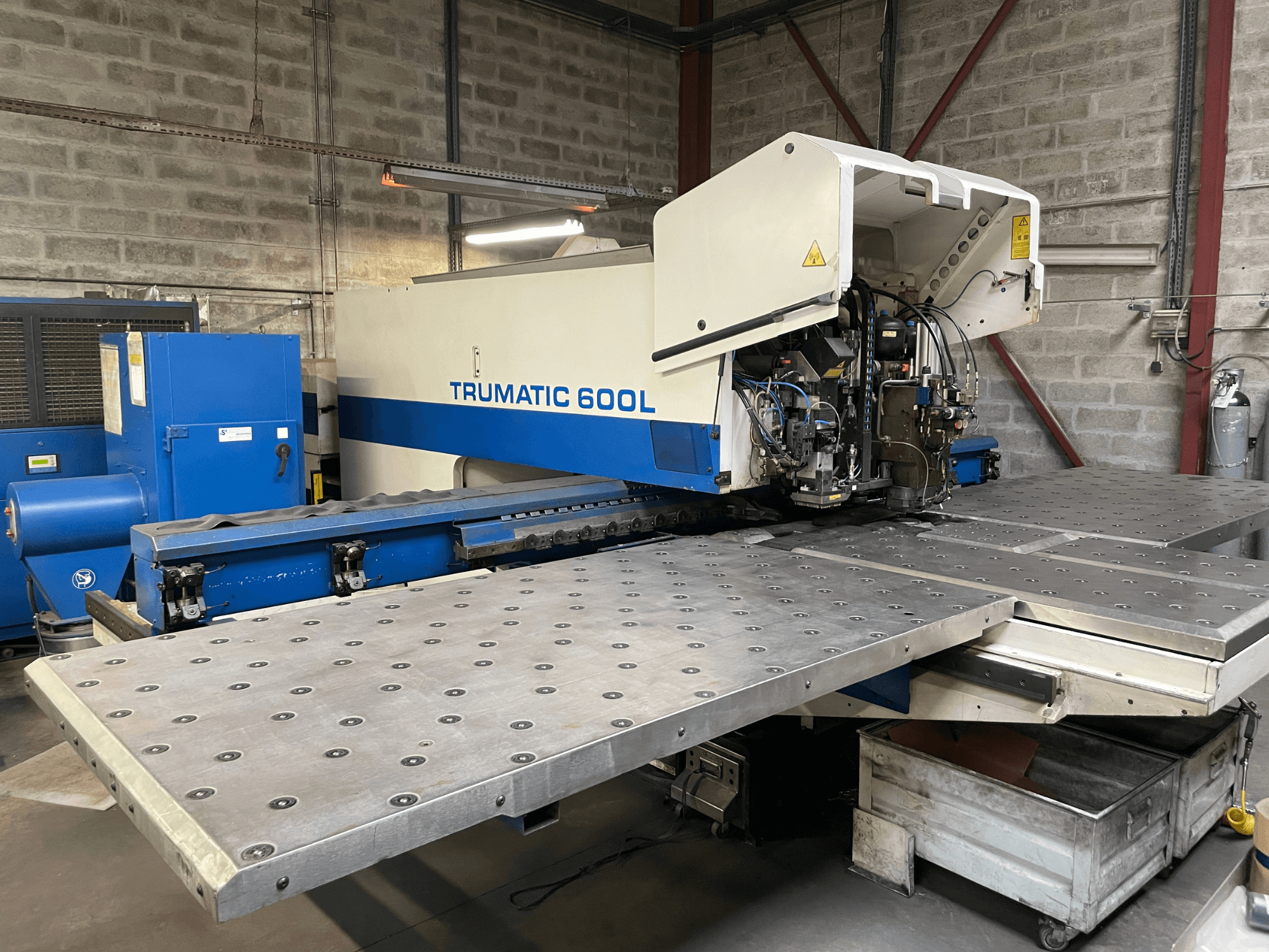 Wycinarka laserowa CO2 TRUMPF TRUMATIC TC 600L, widok z przodu z widocznym stołem do cięcia metalu i panelem sterowania.