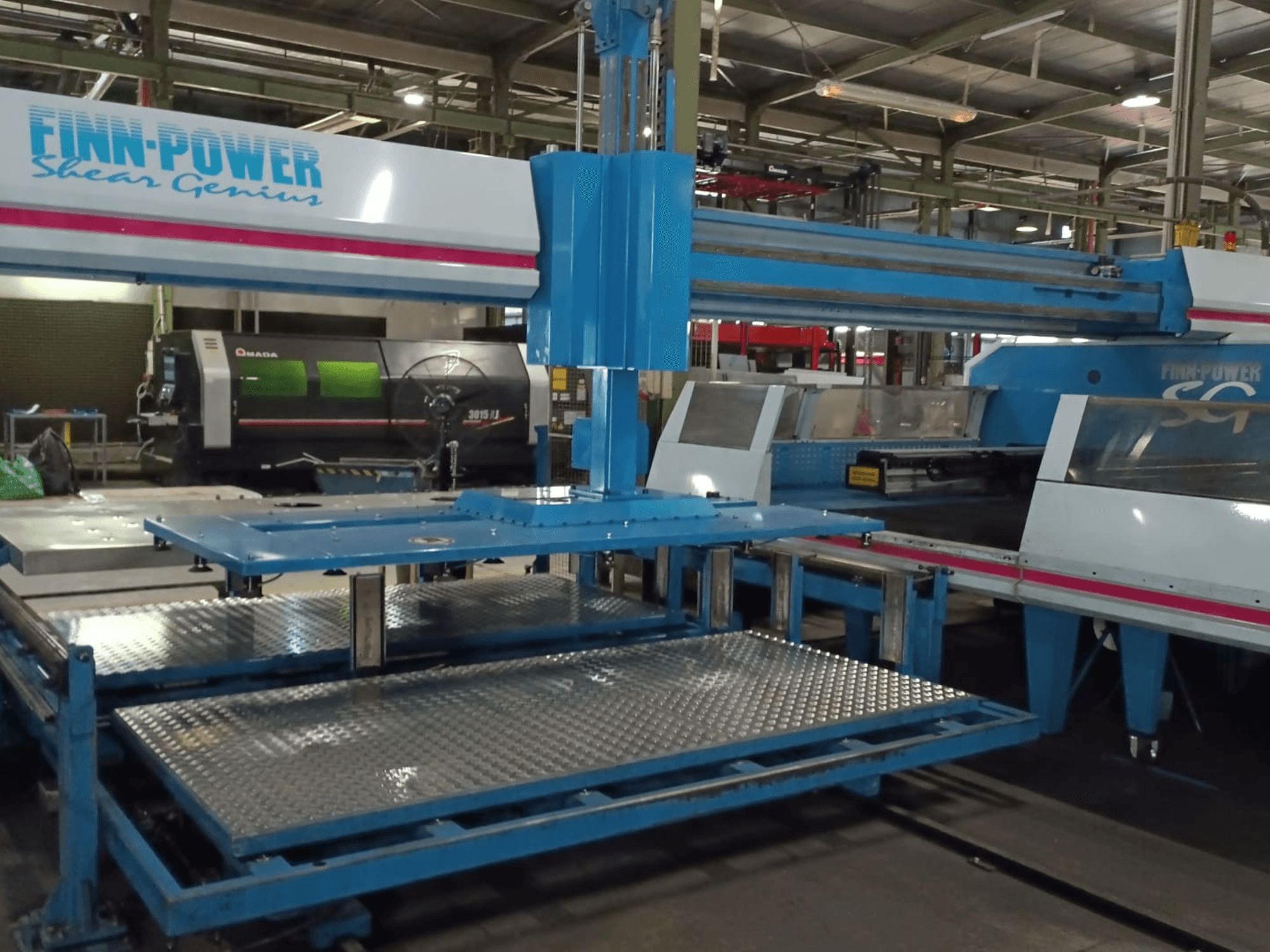 Wykrawarka CNC Finn-Power SG6 „Shear Genius” widziana z przodu, z widocznymi metalowymi stołami i elementami konstrukcyjnymi.