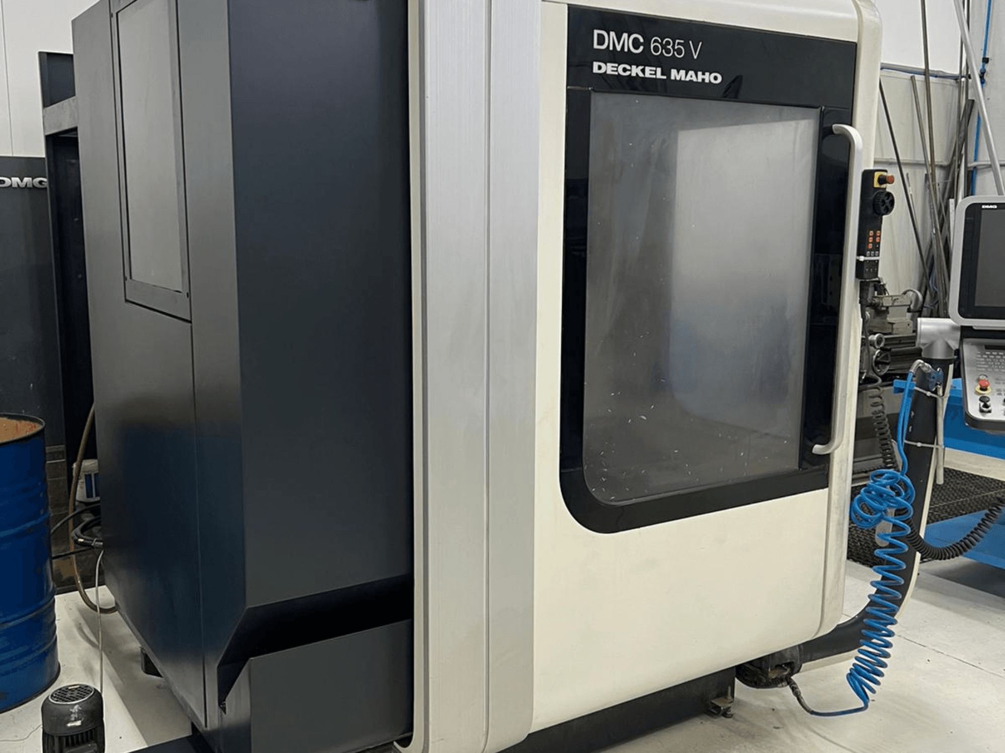 Frezarka DMC 635 V firmy Deckel Maho, widok z boku przedstawiający panel sterowania i częściowo otwarte drzwiczki dostępu.