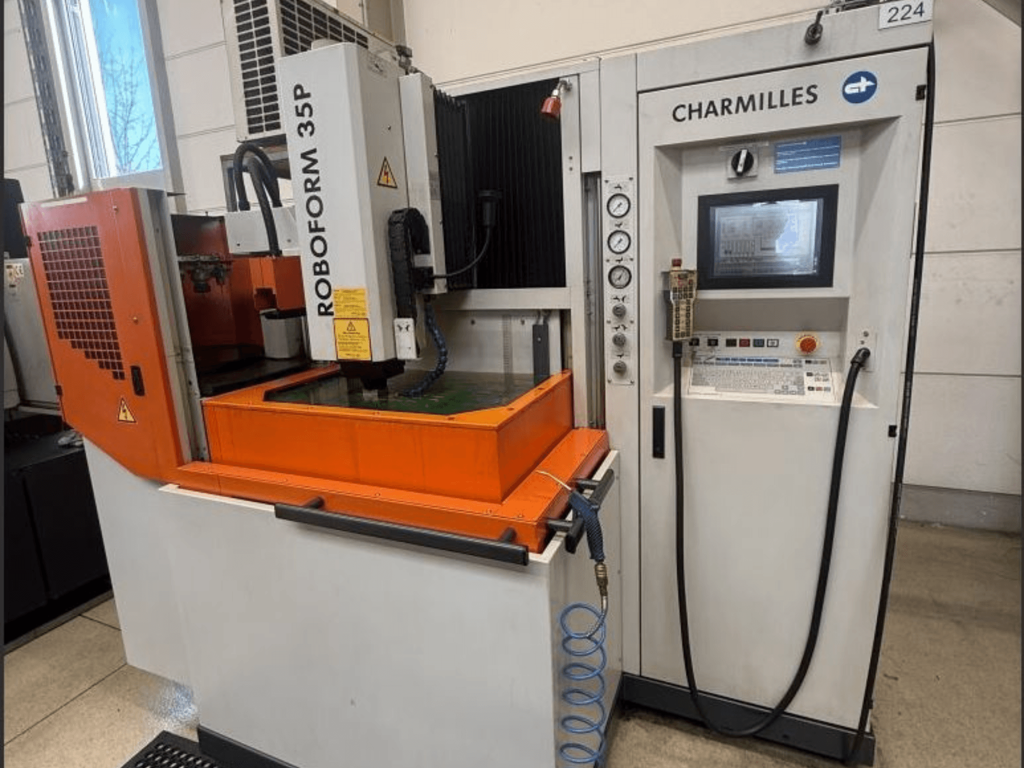 Elektrodrążarka wgłębna ROBOFORM 35P firmy Charmilles, widok z przodu, z panelem sterowania, suwnicą i zbiornikiem płynu podczas pracy.