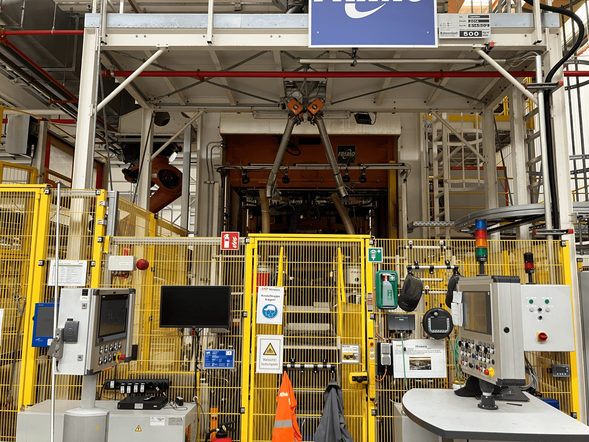 FRIMO NFPP Thermoforming Plant widok z przodu, z panelami sterowania i ogrodzeniem ochronnym w dobrze oświetlonym otoczeniu przemysłowym.