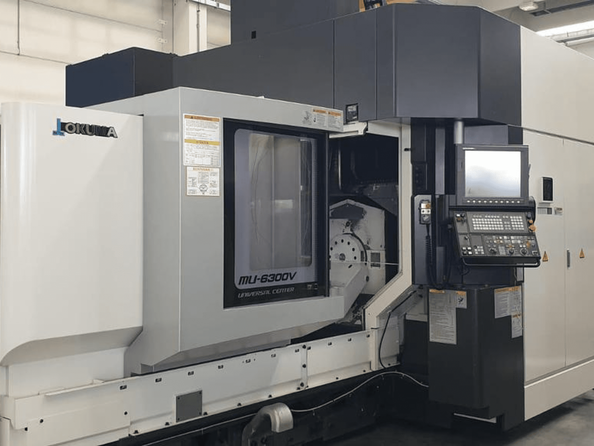 Pionowe centrum obróbcze Okuma MU 6300 V, widok z przodu przedstawiający panel sterowania i szczegóły obszaru obróbki.