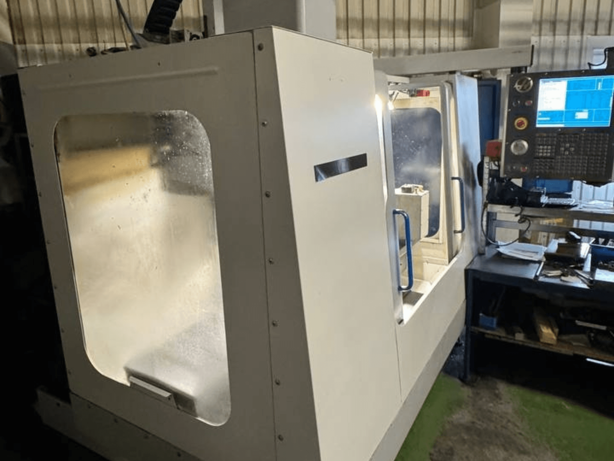 Pionowe centrum obróbcze HAAS VCE 750 w widoku z boku, z panelem sterowania i przezroczystą obudową bezpieczeństwa.