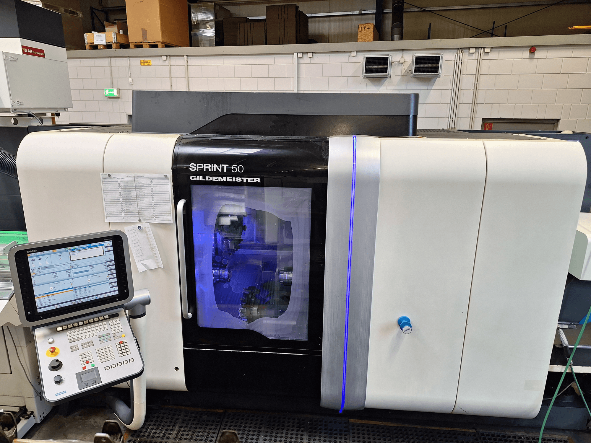 Tokarka pozioma DMG Sprint 50 2T, widok z przodu, z panelem sterowania i przezroczystą obudową prezentującą maszynę wewnątrz.