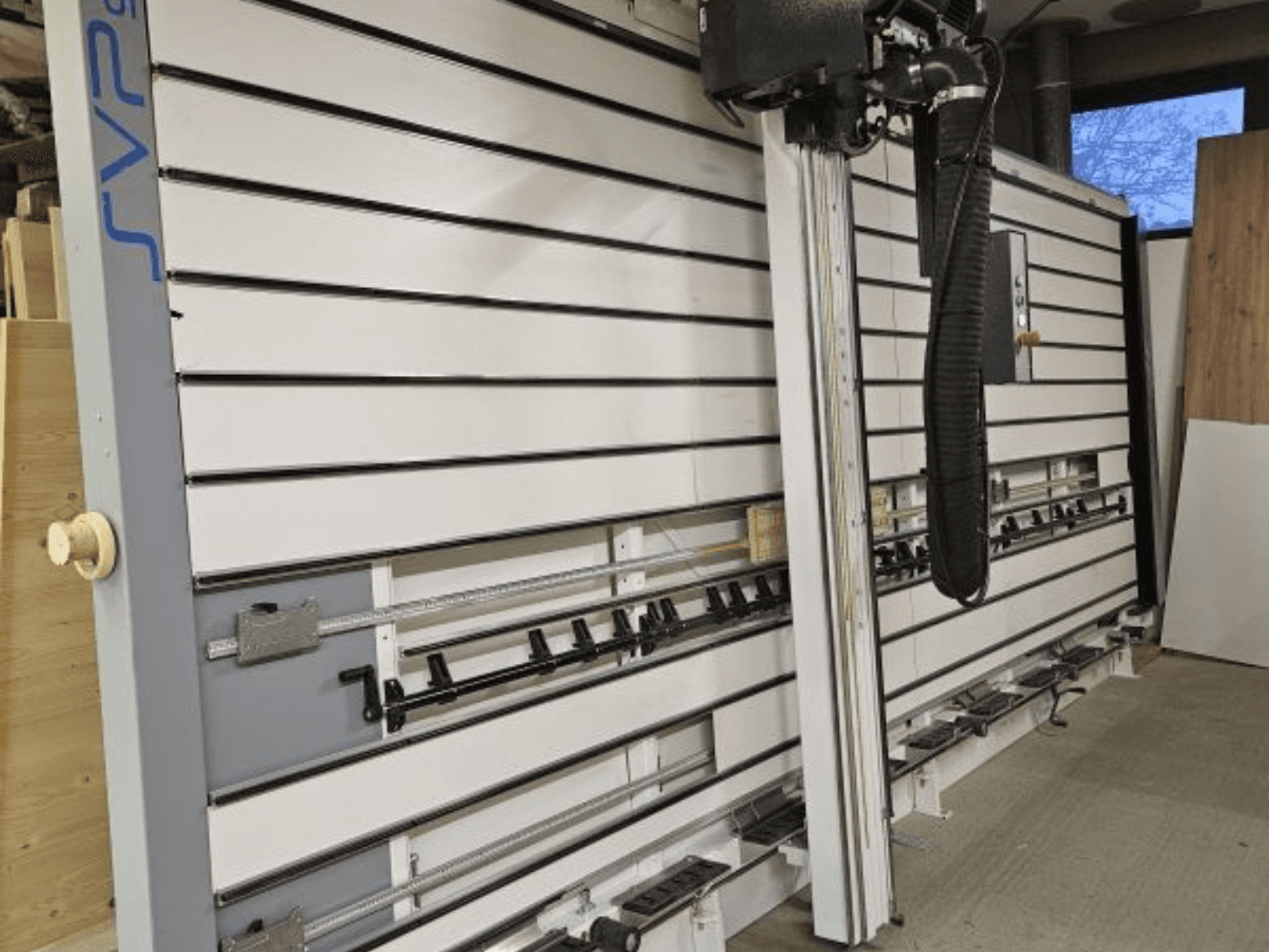 Przesuwna pilarka panelowa SVP w warsztacie, widok z przodu, wyposażona w regulowane prowadnice i górny system odsysania pyłu.