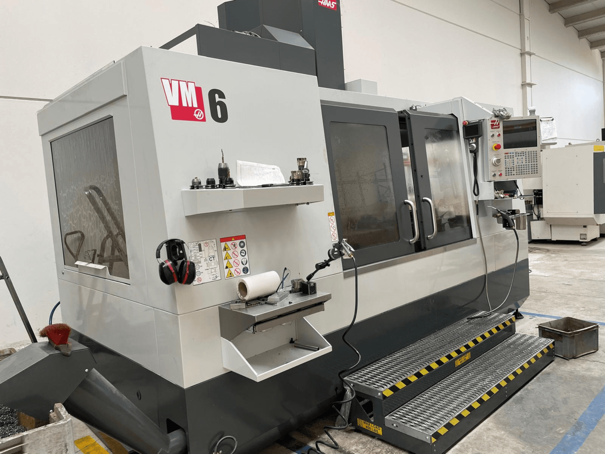 Pionowe centrum obróbcze Haas VM-6, widok z przodu przedstawiający panel sterowania, uchwyty narzędzi i zabezpieczenia.