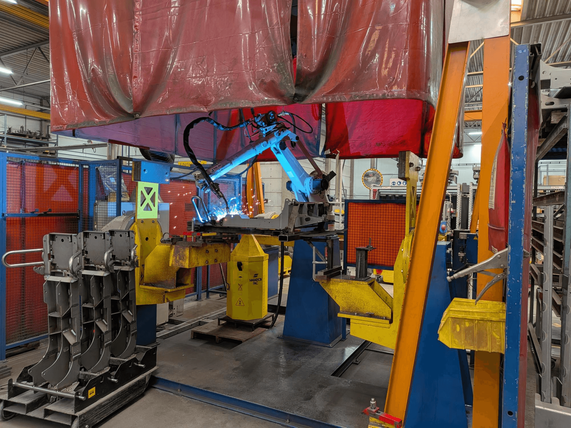 Robot spawalniczy OTC Daihen DR4200 w akcji, widok z przodu, z jasnoniebieskim łukiem spawalniczym i osłoną ochronną.