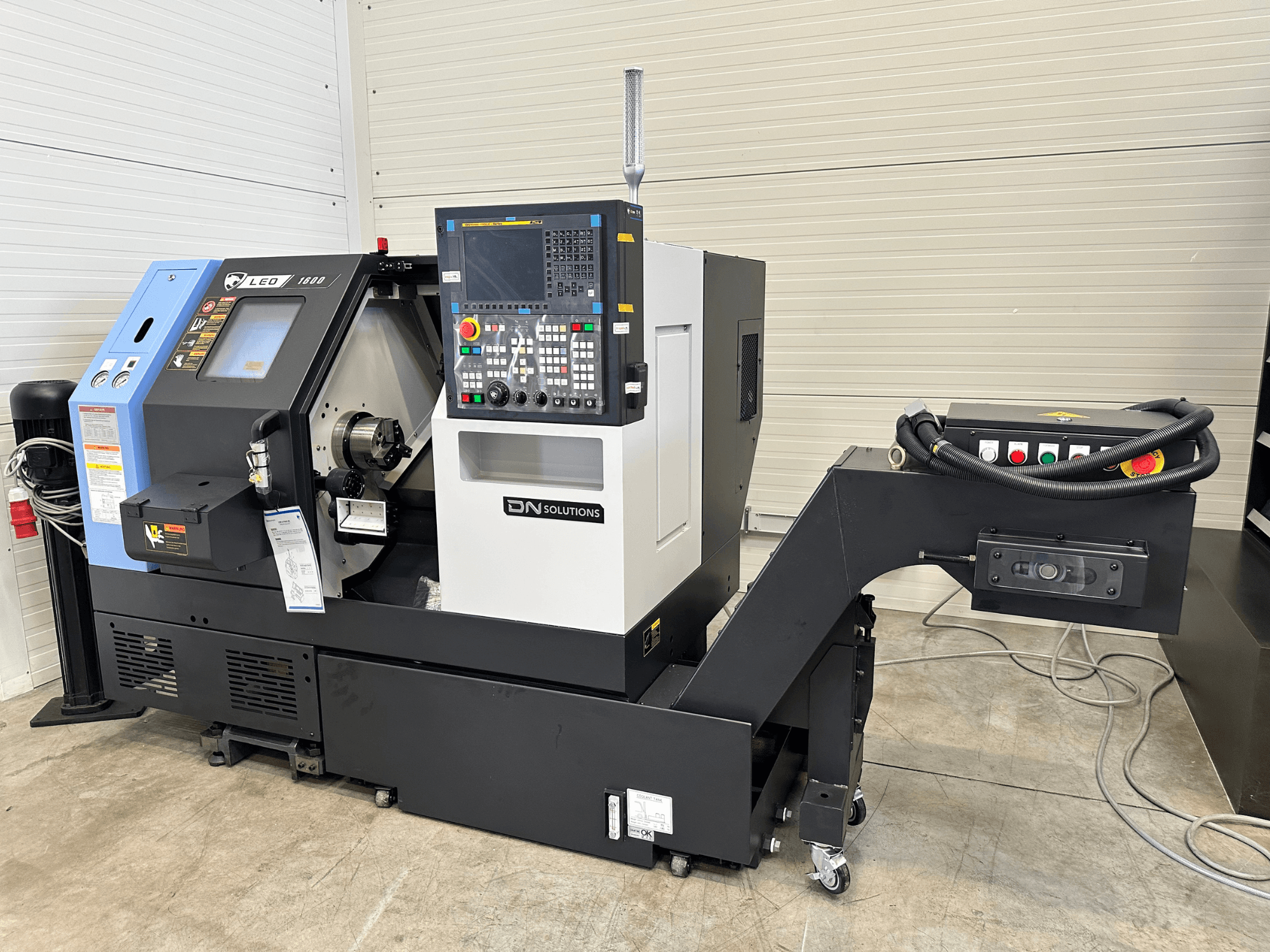 Widok z przodu centrum frezarskiego DN SOLUTIONS Leo 1600 z cyfrowym panelem sterowania i uchwytem narzędziowym na czarnej podstawie.