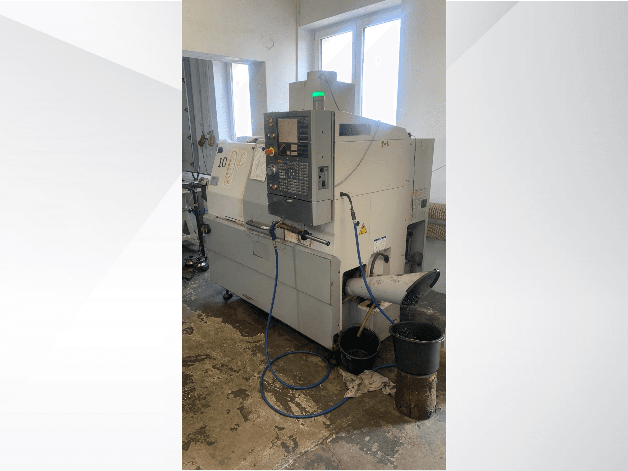 Model maszyny CNC Haas z panelem sterowania, widok z boku, z przewodem chłodziwa, zsypem odpadów i pojemnikami do przechowywania poniżej.