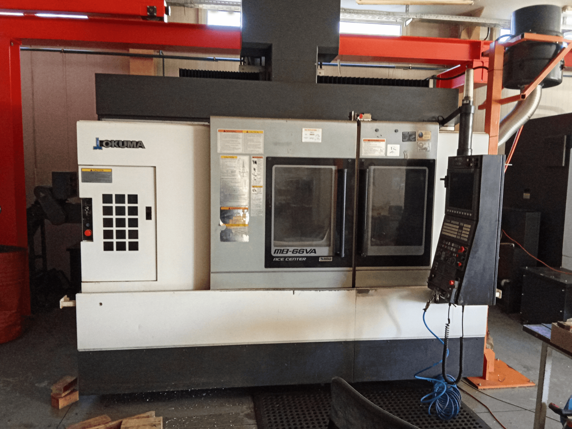 Pionowe centrum obróbcze Okuma MB-66VA, widok z przodu przedstawiający panel sterowania i podwójne okna podglądu umożliwiające dostęp do narzędzi.