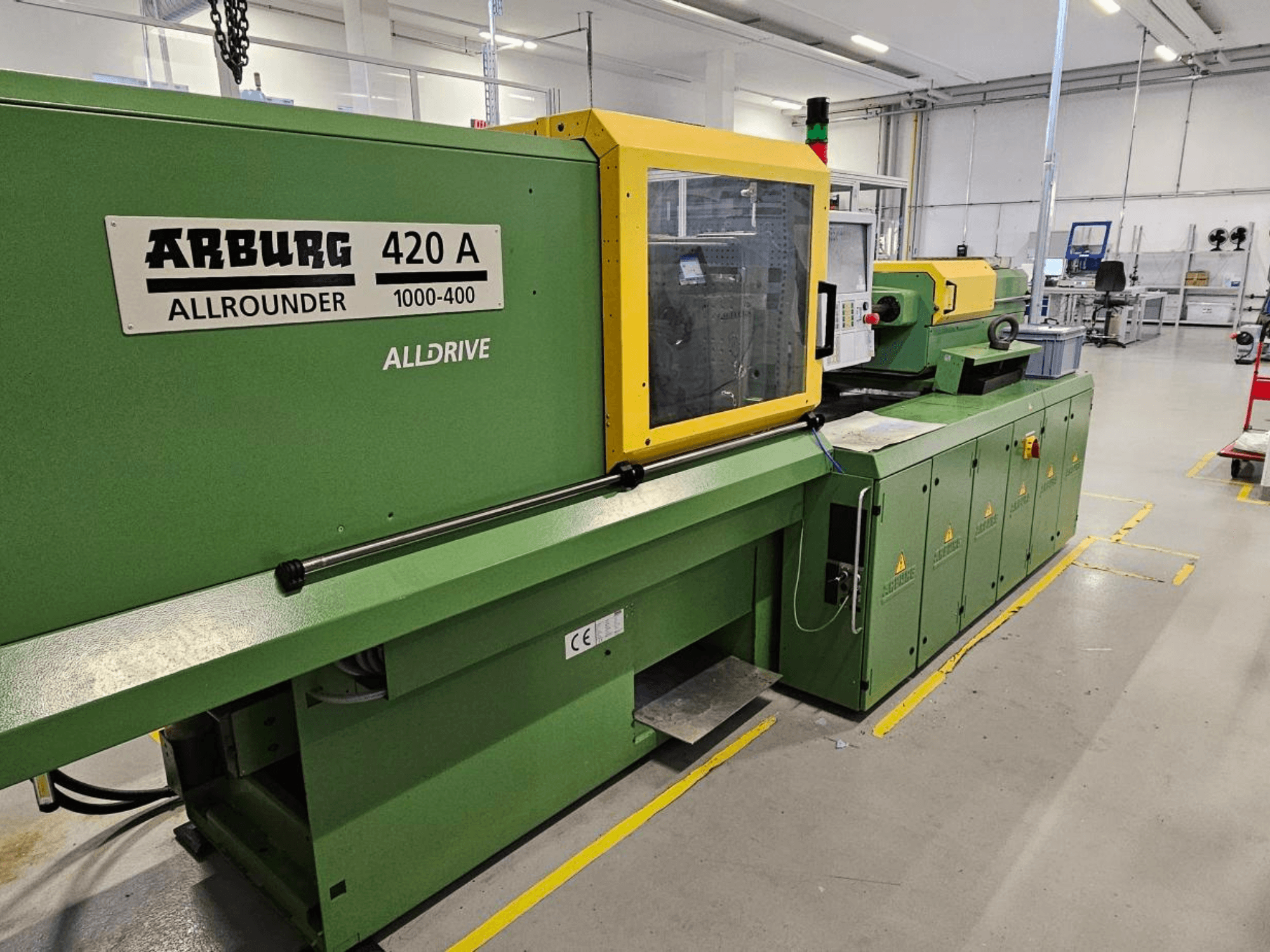 ARBURG 420 A Allrounder 1000-400, widok z przodu; zielona maszyna z żółtym panelem, ekranem dotykowym i funkcjami bezpieczeństwa.
